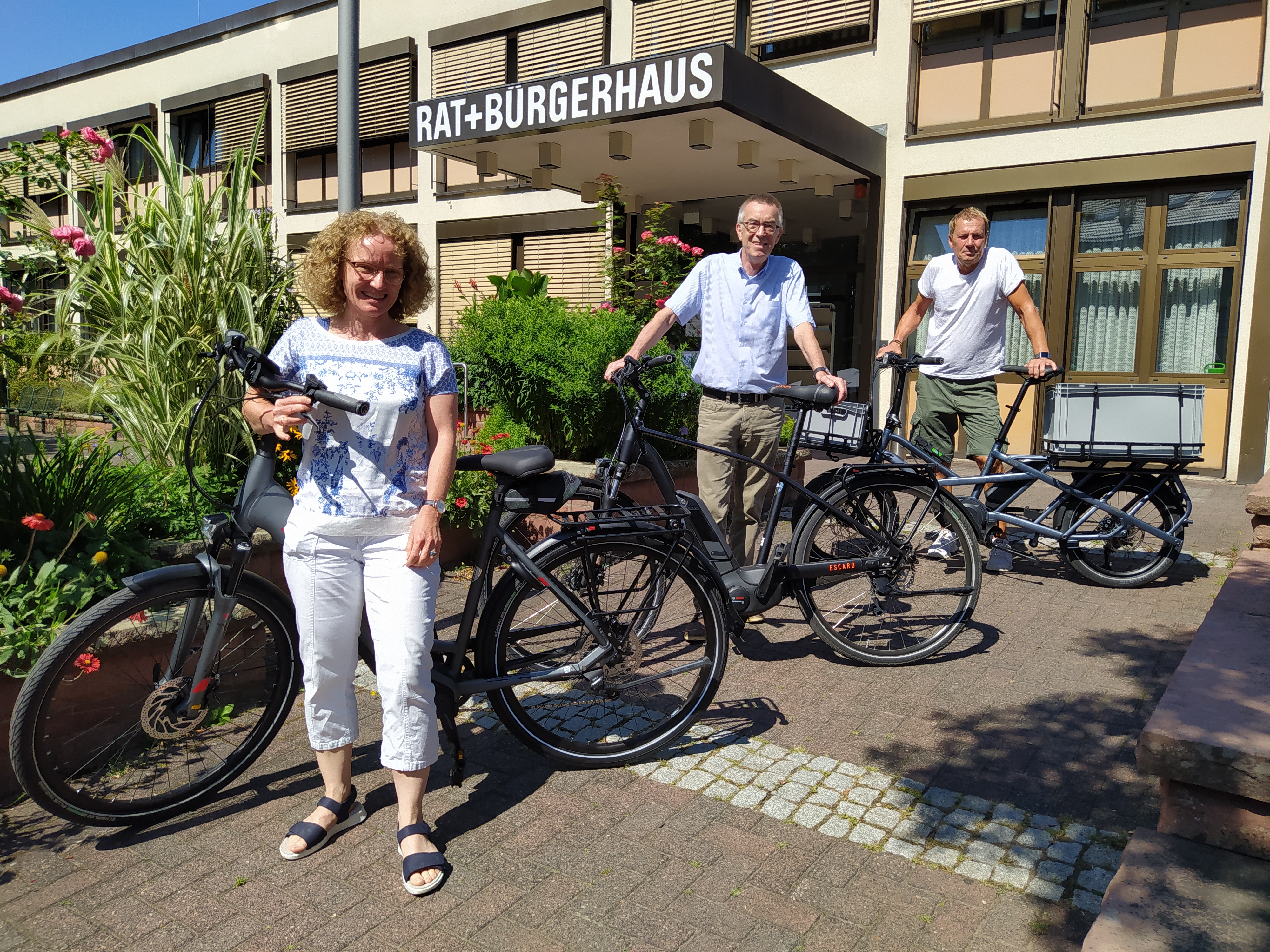 Franz Jirasek mit zwei Mitarbeiter/innen und den neuen E-Bikes vor dem Rathaus.
