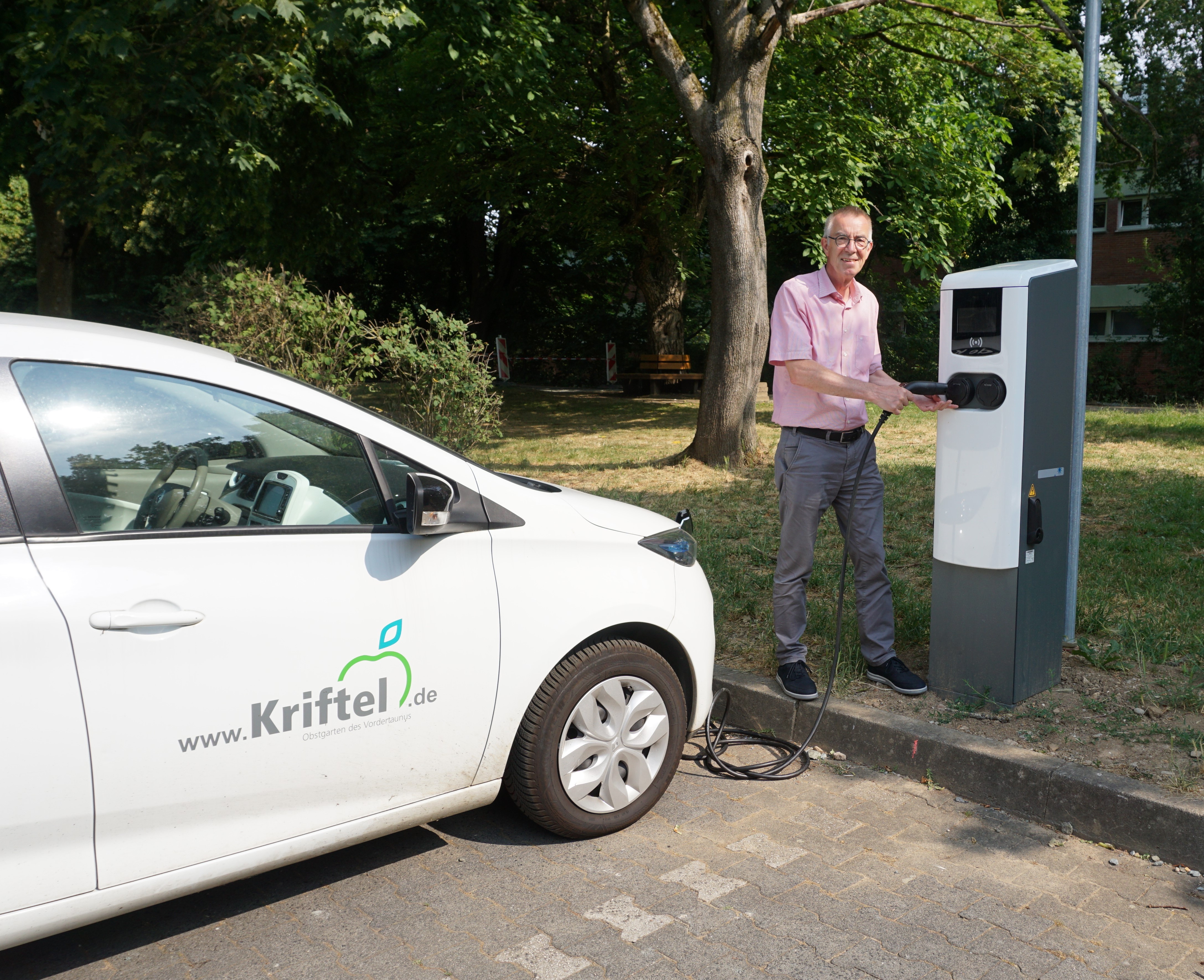 Jirasek mit Elektroauto der Gemeinde vor neuer Ladesäule an der Schwarzbachhalle.