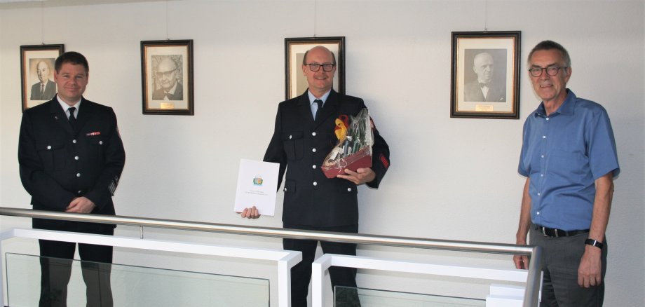 Harald Burg mit Urkunde und Geschenk zwischen Gemeindebrandinspektor Kilian und Erstem Beigeordneten Jirasek.