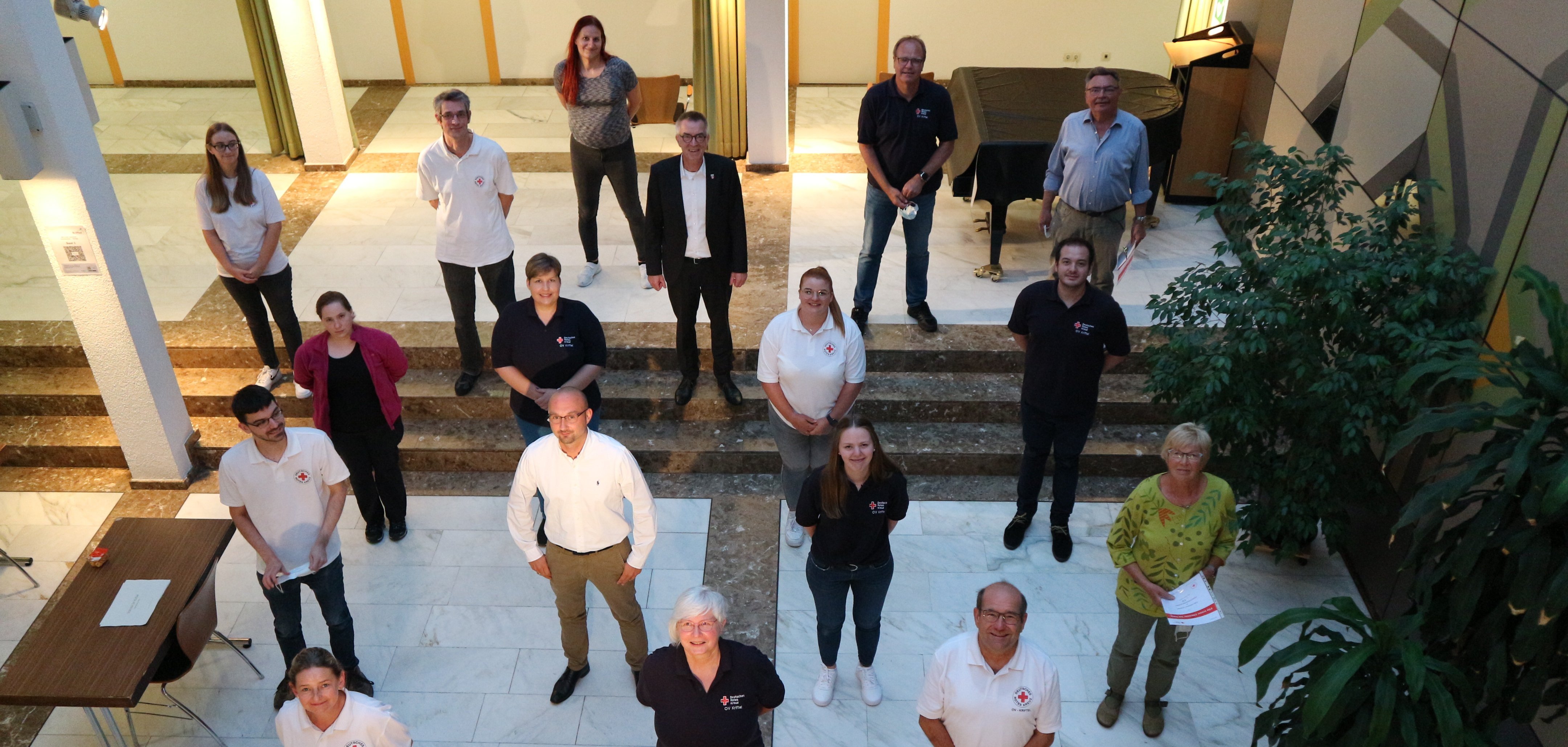 Die DRK MItglieder schauen im Rathaus-Foyer nach oben in die Fotolinse.
