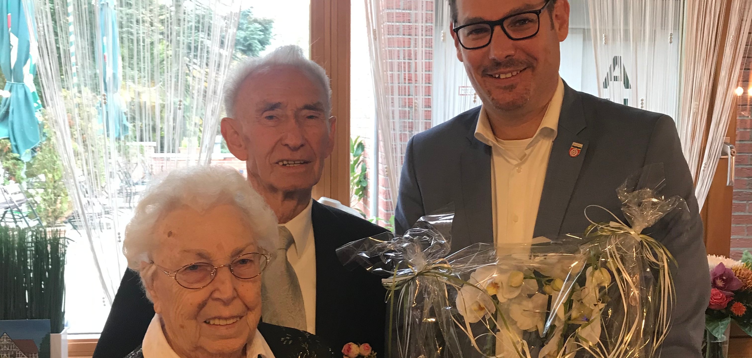 Bürgermeister Seitz mit dem Ehepaar Windl und einem Blumengeschenk im Restaurant Schwarzbachhallen.