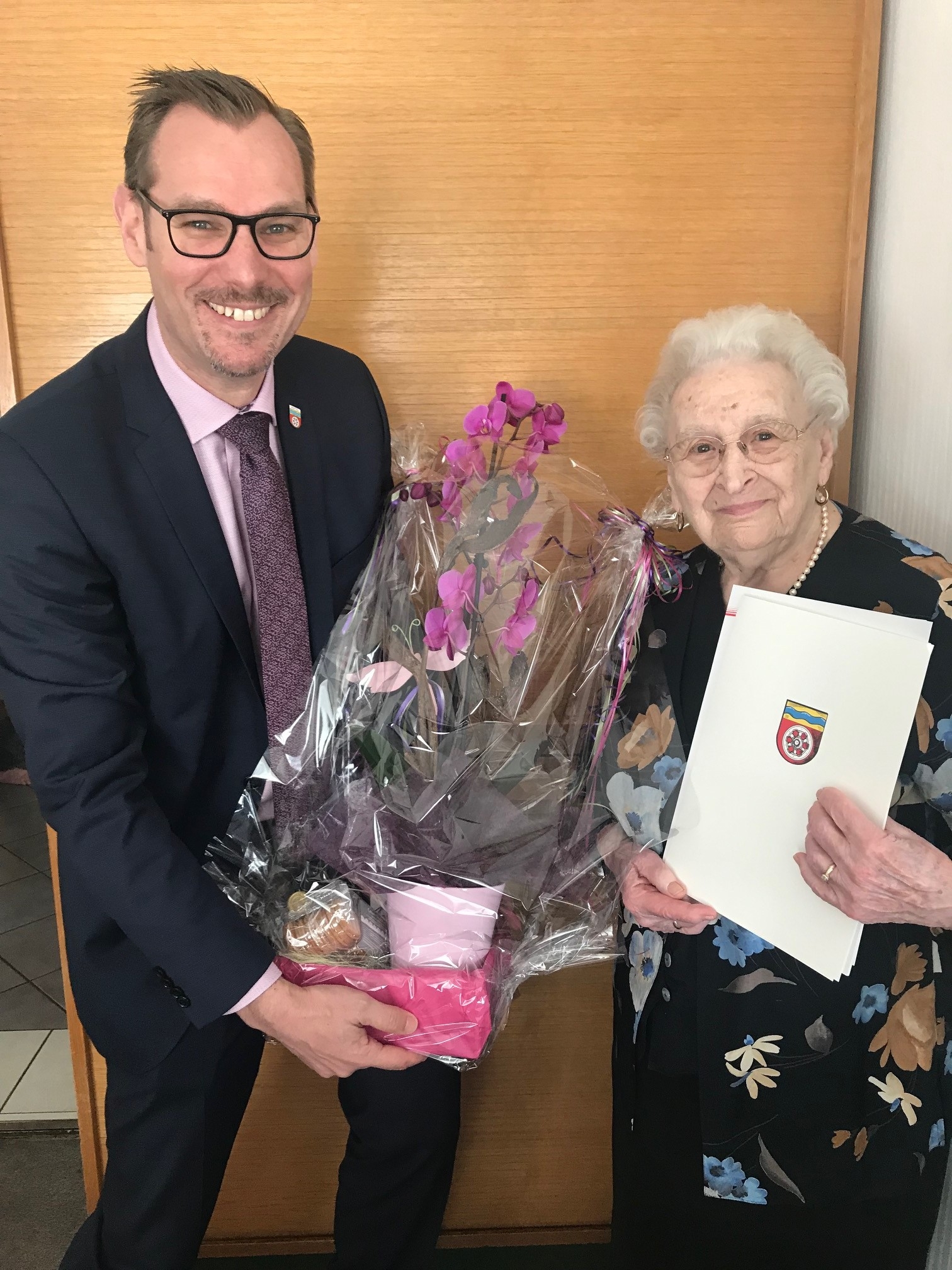Bürgermeister Christian Seitz übergibt Elfriede Pfeil Urkunden und Blumen.
