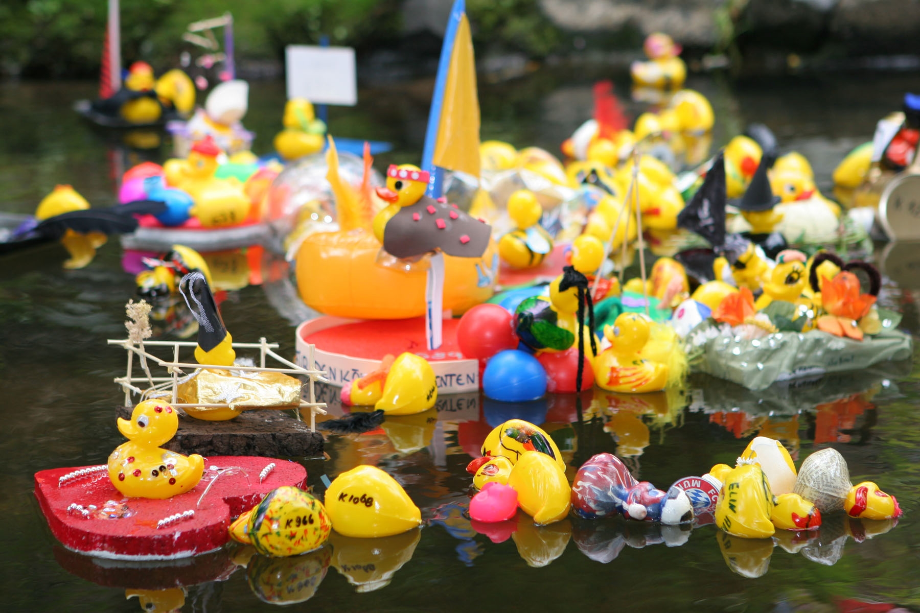 Viele kleine geschmückte Enten im Wasser.