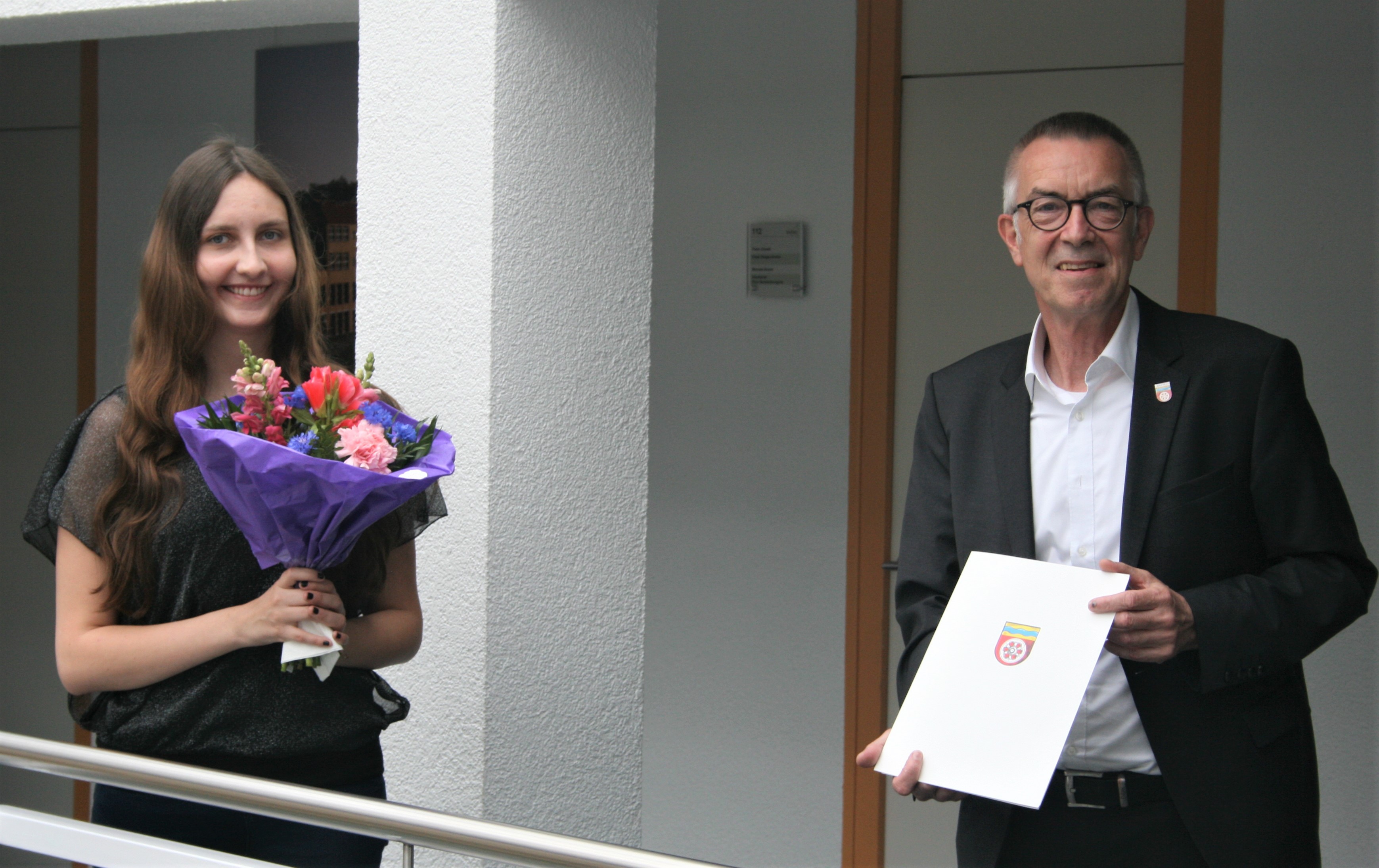 Anna Weis mit Franz Jirasek, Blumenstrauß und Urkunde.