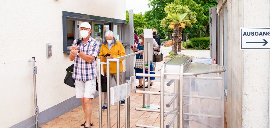 Die ersten Besucher passieren mit Maske die Parkbad-Kasse.