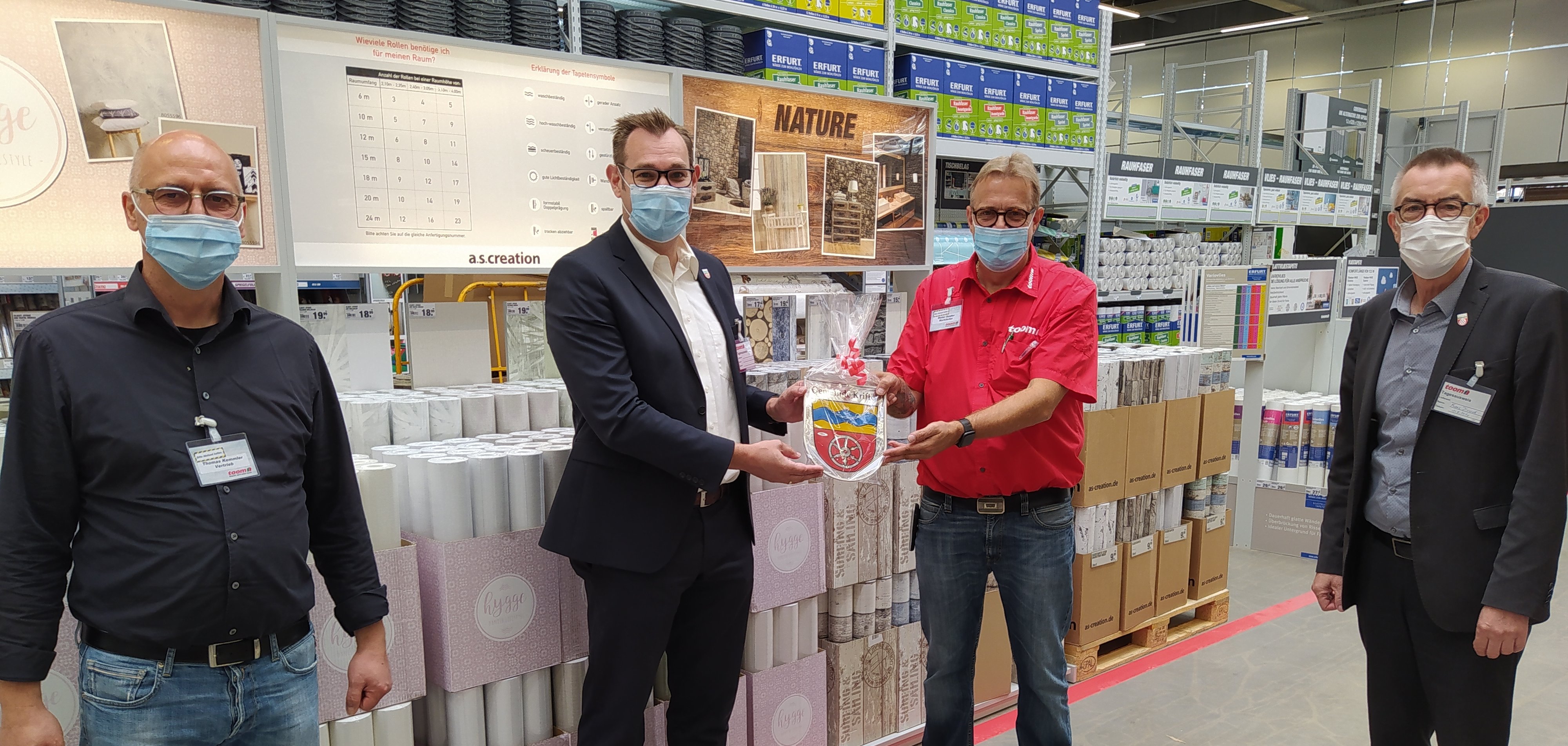 Bürgermeister Christian Seitz übergibt der toom-Marktleitung das Kriftel-Wappen aus Glas.