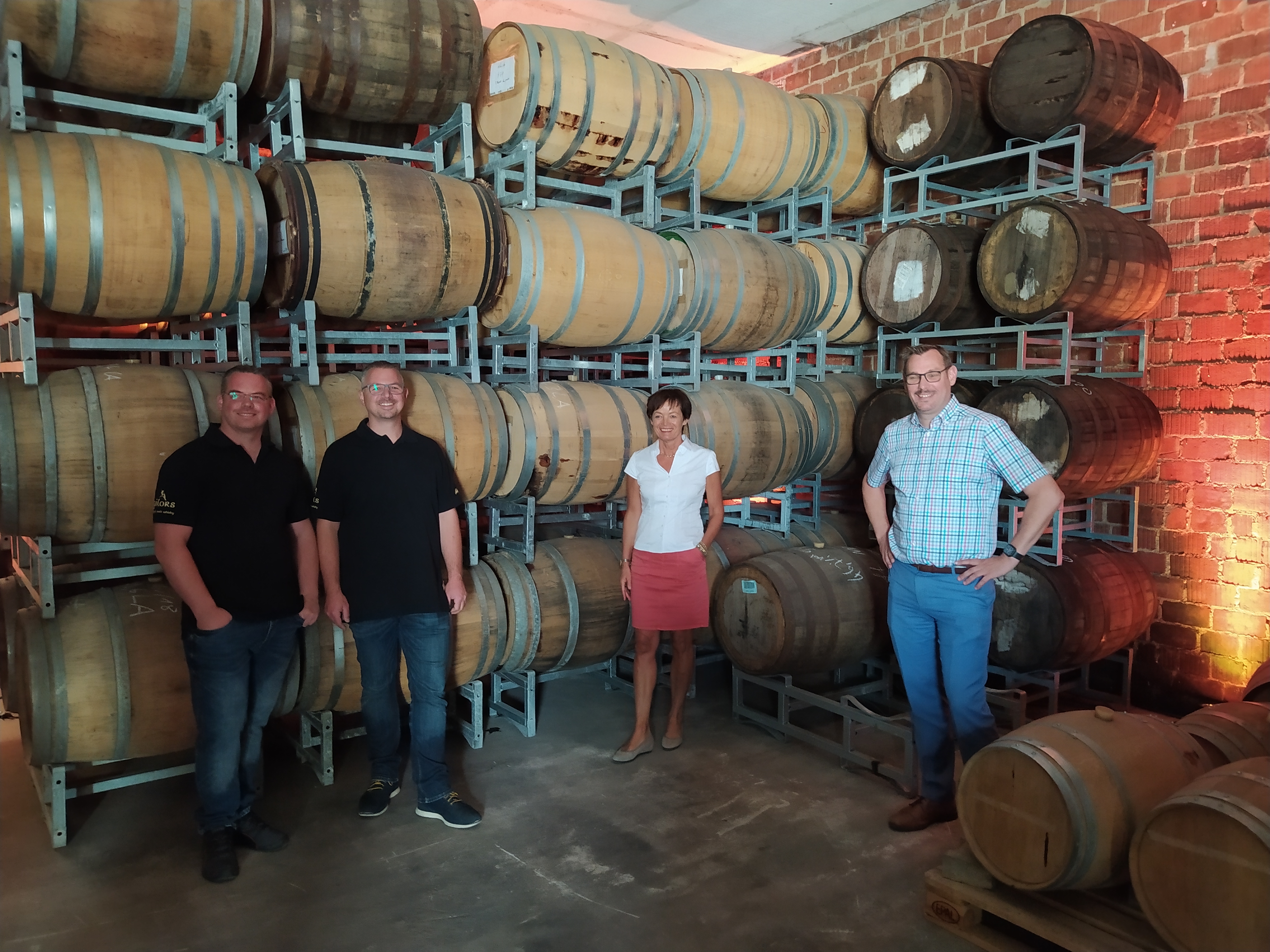 Europaministerin Licia Puttrich mit Bürgermeister Seitz und den Brüdern Henrich vor den Whisky-Fässern.