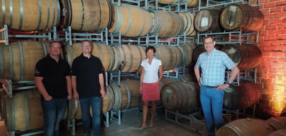 Europaministerin Licia Puttrich mit Bürgermeister Seitz und den Brüdern Henrich vor den Whisky-Fässern.
