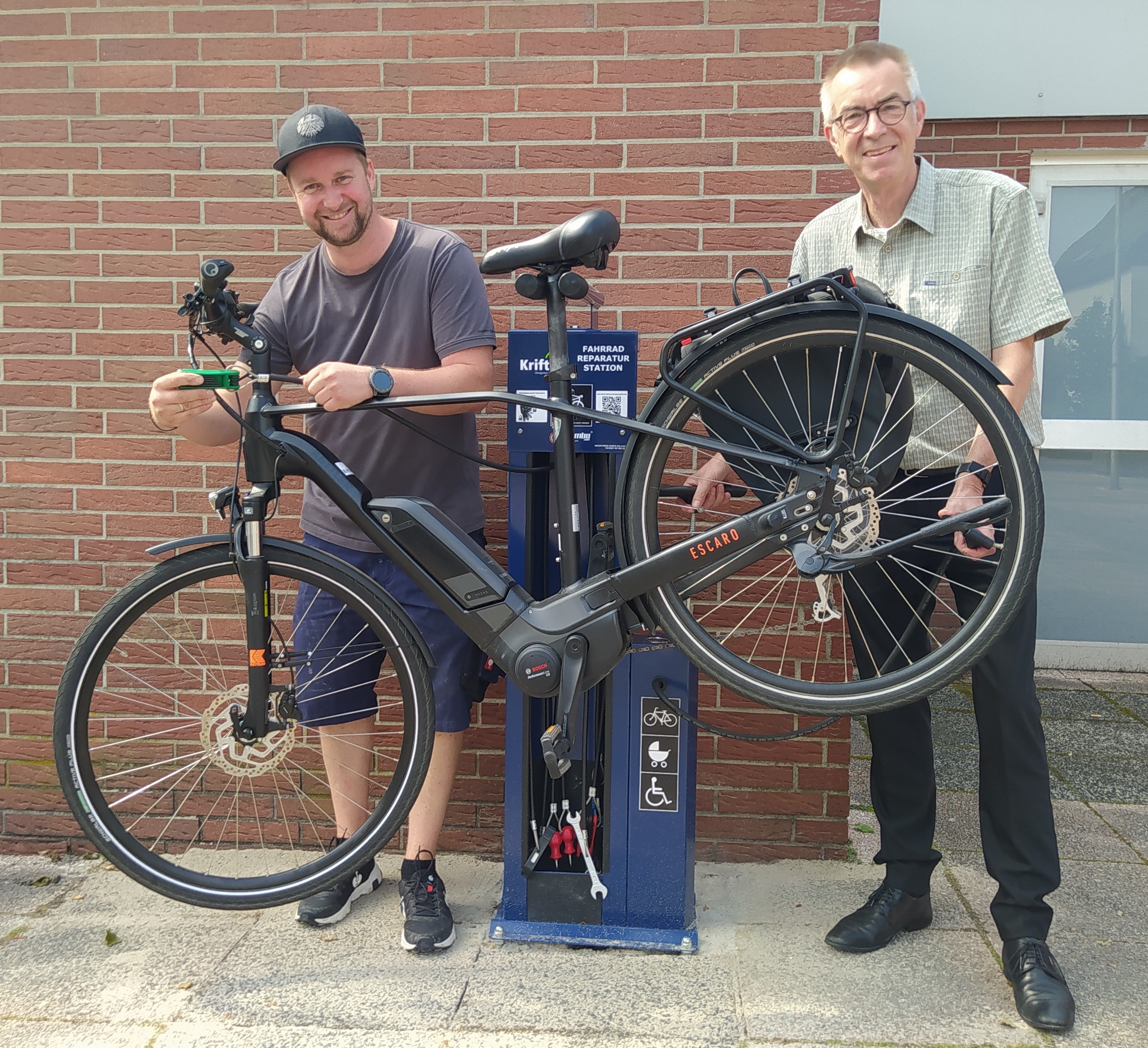 Jirasek und Hausmeister mit Fahrrad an der Station.