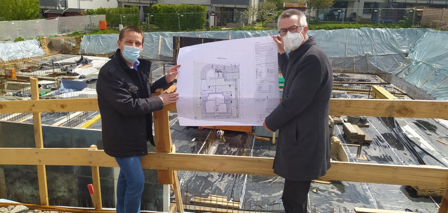Franz Jirasek und Jürger Röll an der Baustelle. Sie halten einen Bauplan in der Hand.