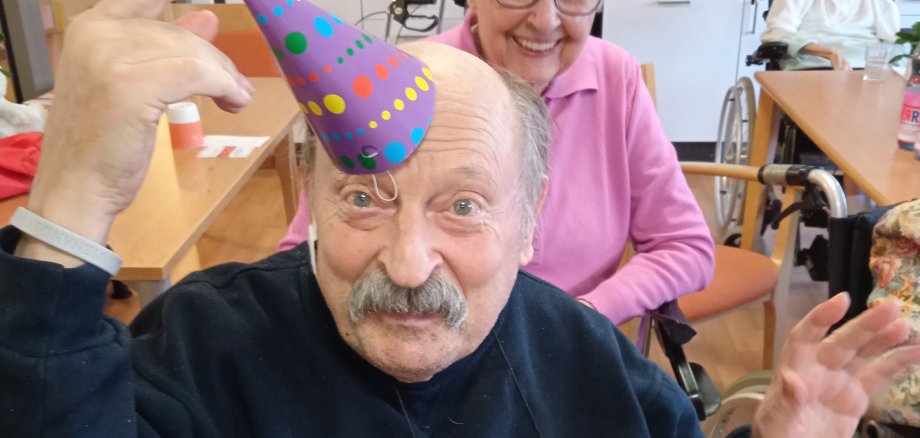 Ein älterer Herr hält sich eine Kappe auf die Stirn.