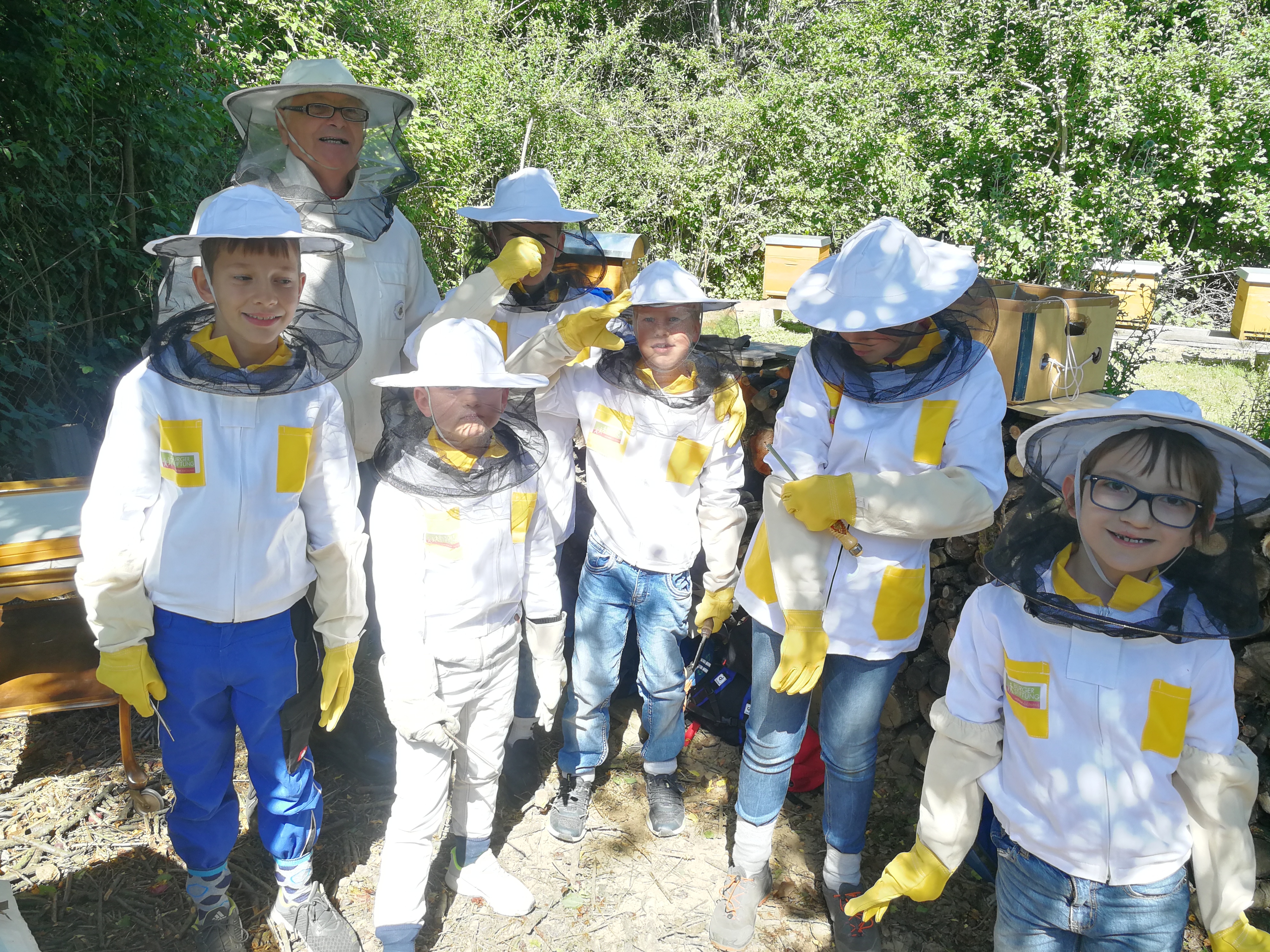 Sechs Kinder in kleinen Imker-Schutzanzügen.