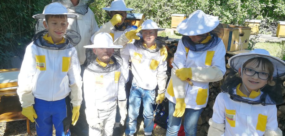 Sechs Kinder in kleinen Imker-Schutzanzügen.
