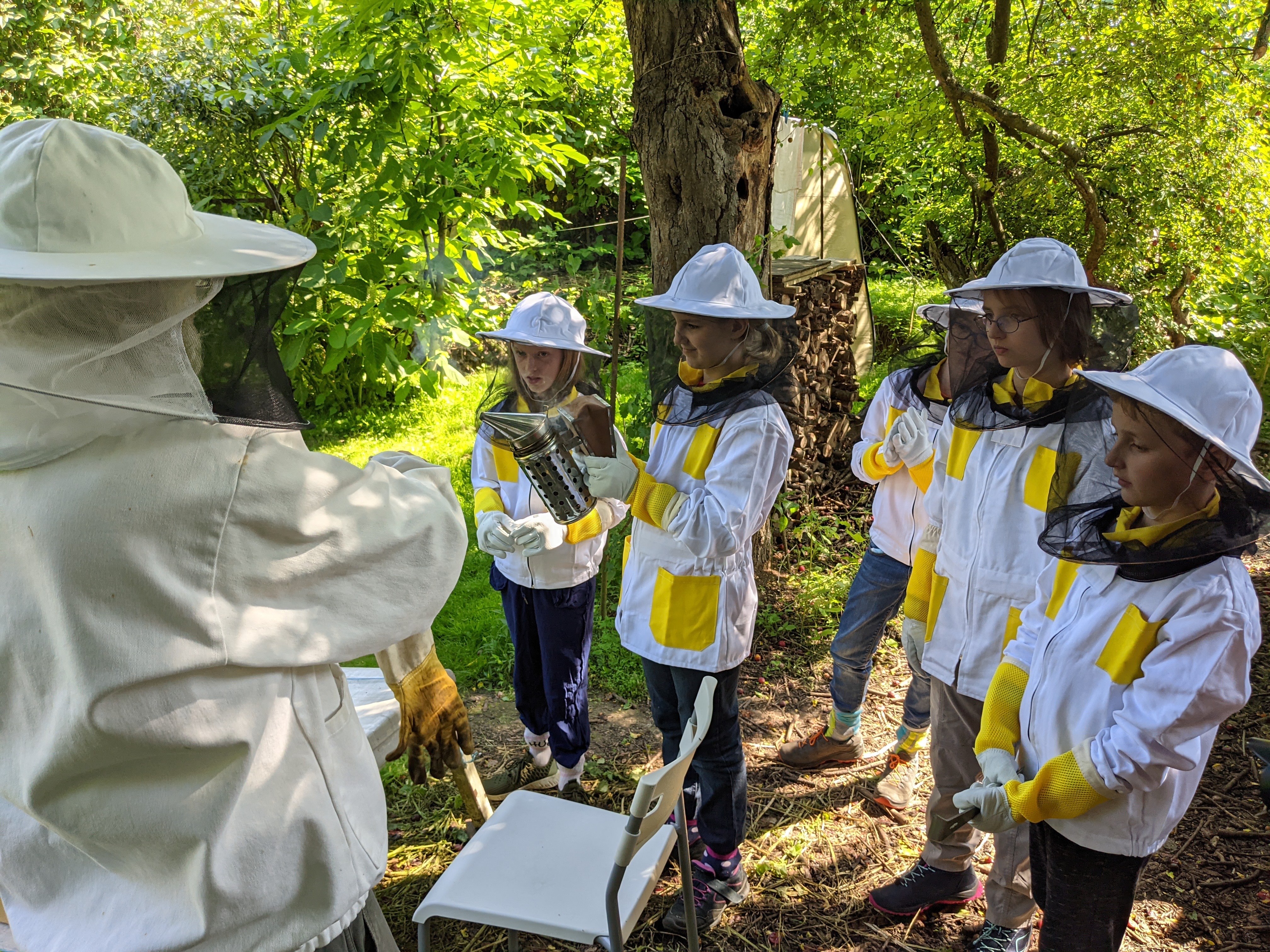 Der Imker und die Kinder in Schutzanzügen.