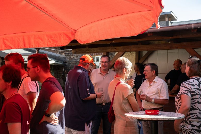 Menschen unterhalten sich unter Sonnenschirmen.
