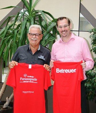 Mister Ferienspiele Didi Dehyle mit Bürgermeister Seitz. Sie halten rote Shirts in der hand.