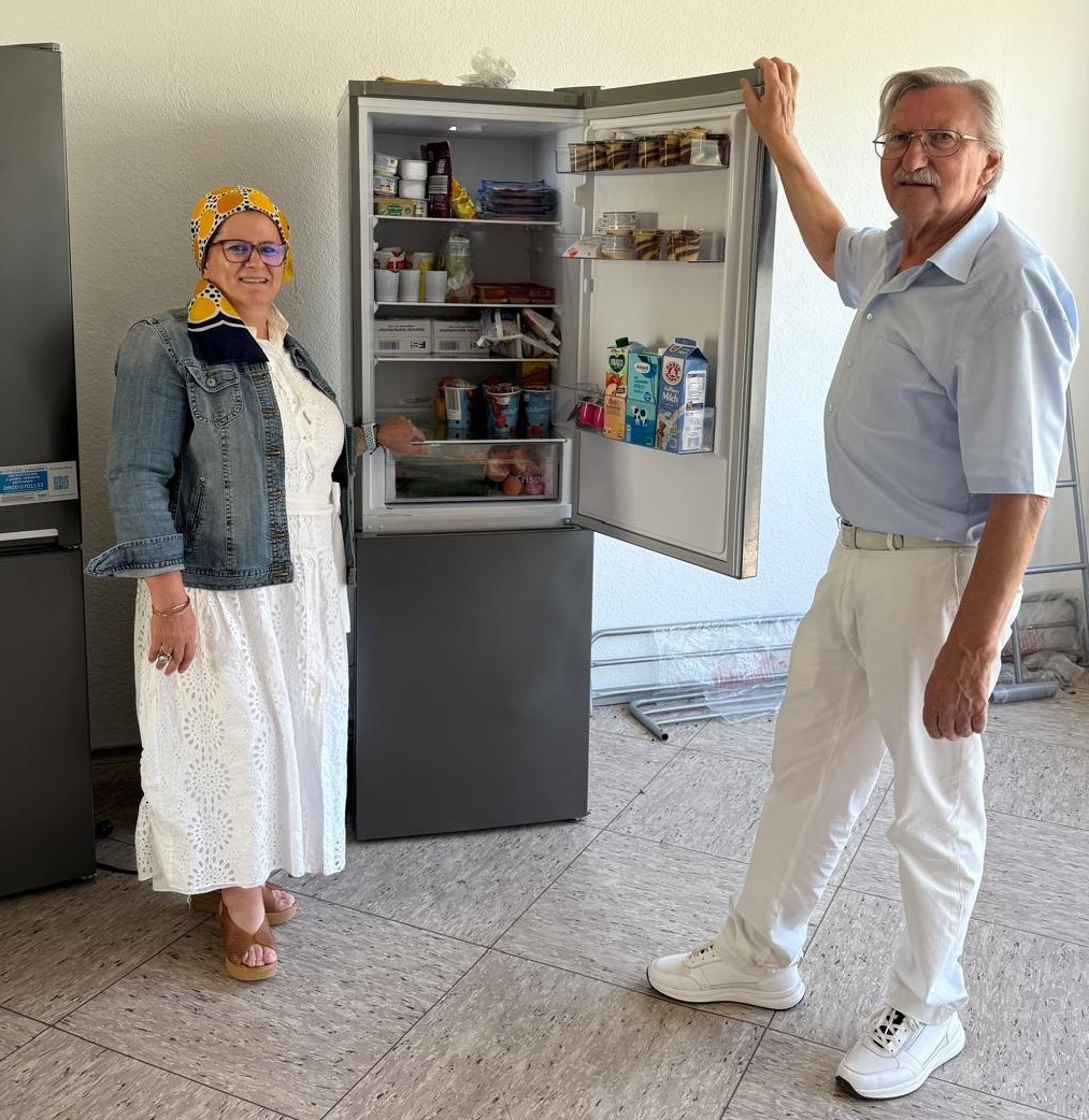 Sozialarbeiterin und Integrationslotse vor einem vollen Kühlschrank.