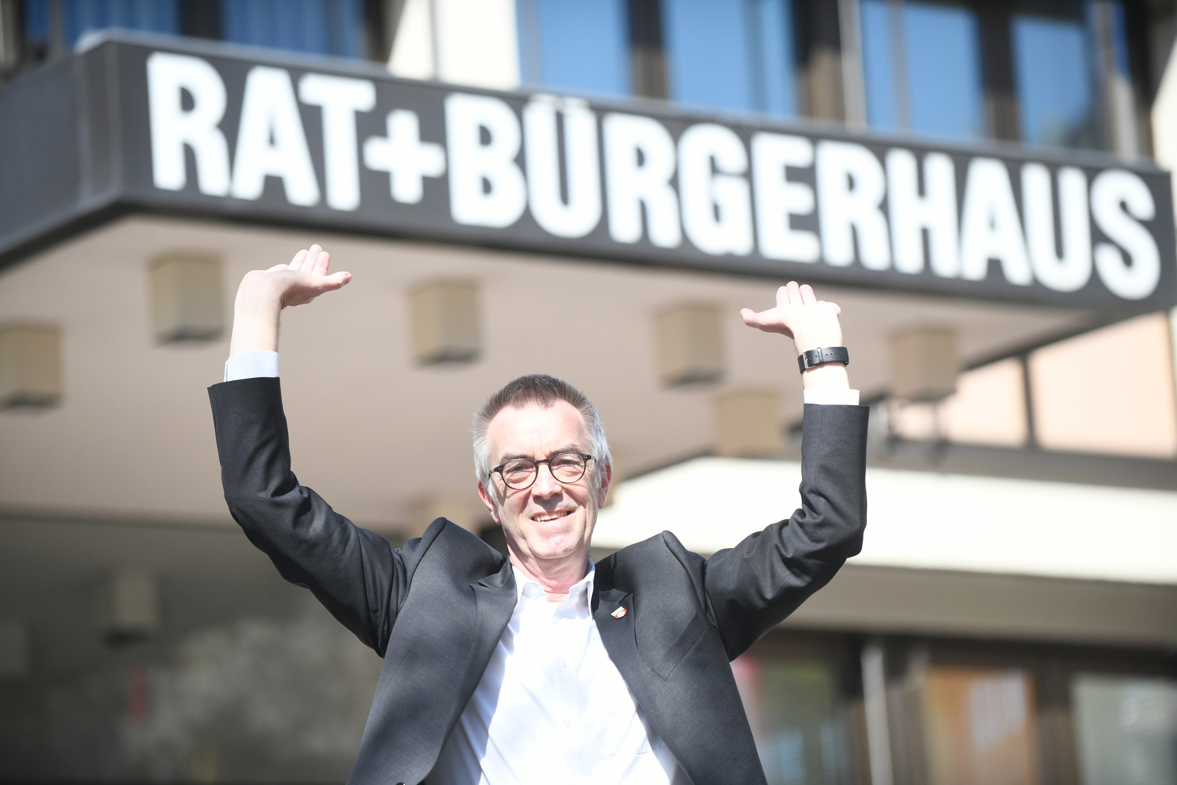 Franz Jirasek vor dem Rathaus. Er hebt die Hände hoch, als wollte er es stützen.