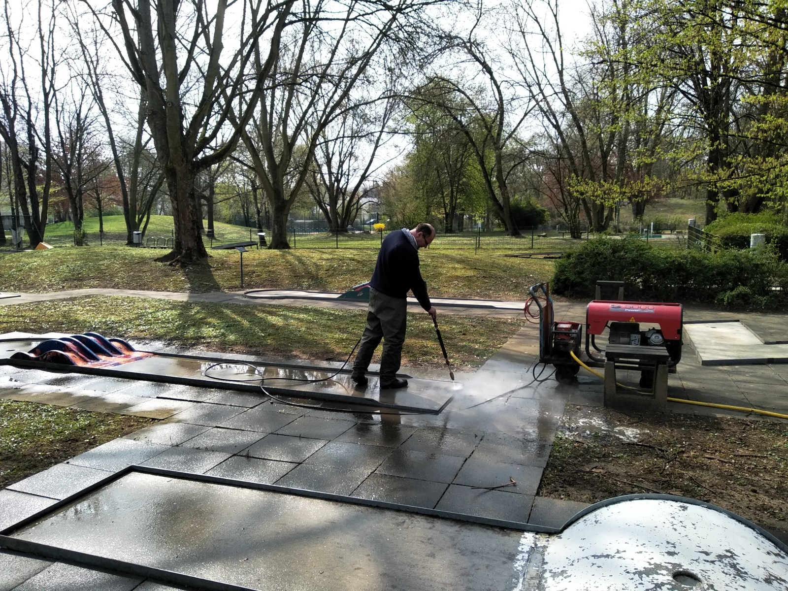 Ein MItarbeiter des Bauhofes spritzt die Minigolfbahnen ab.