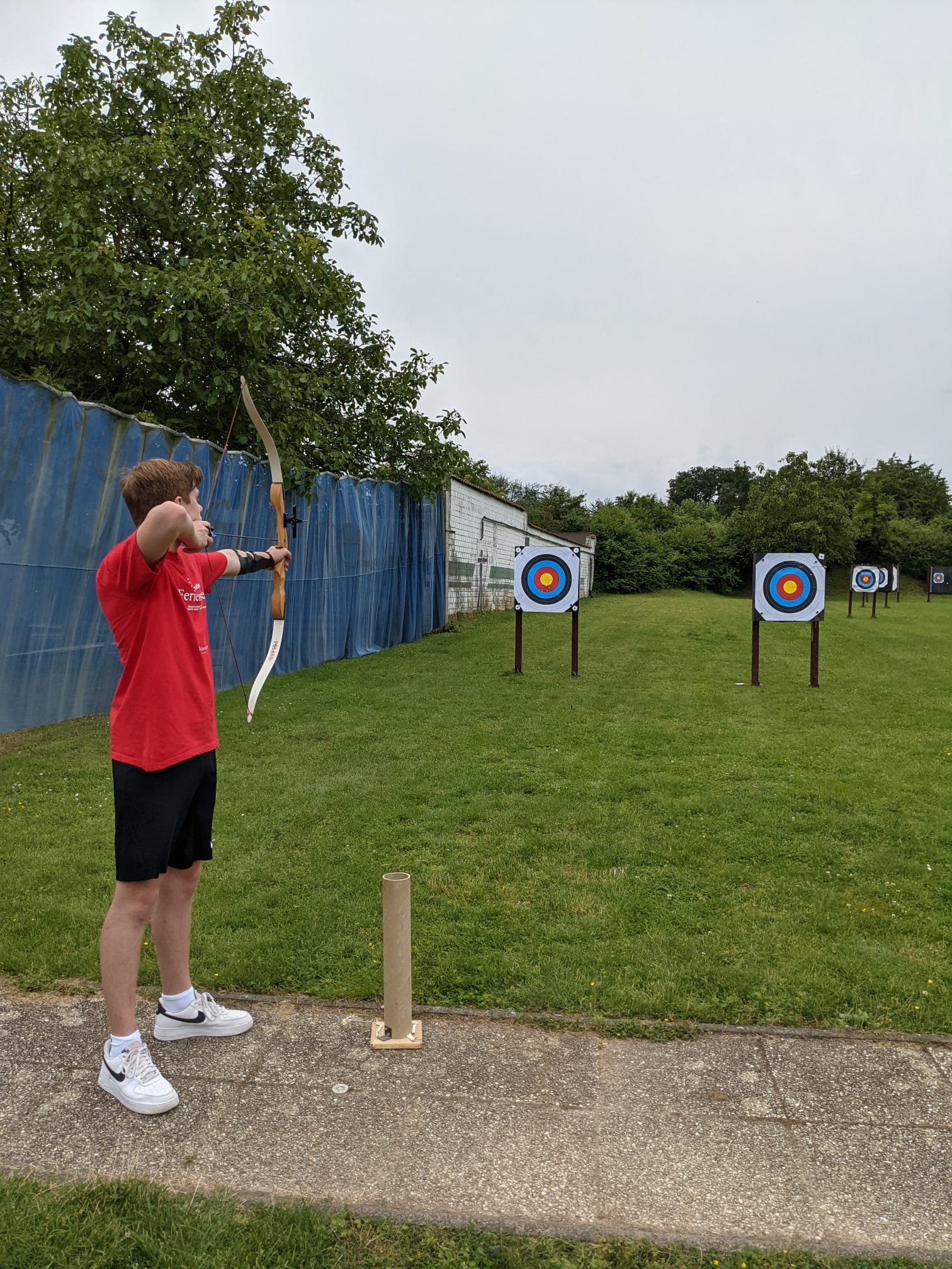 Ein Junge spannt den Bogen und zielt auf eine Zielscheibe.