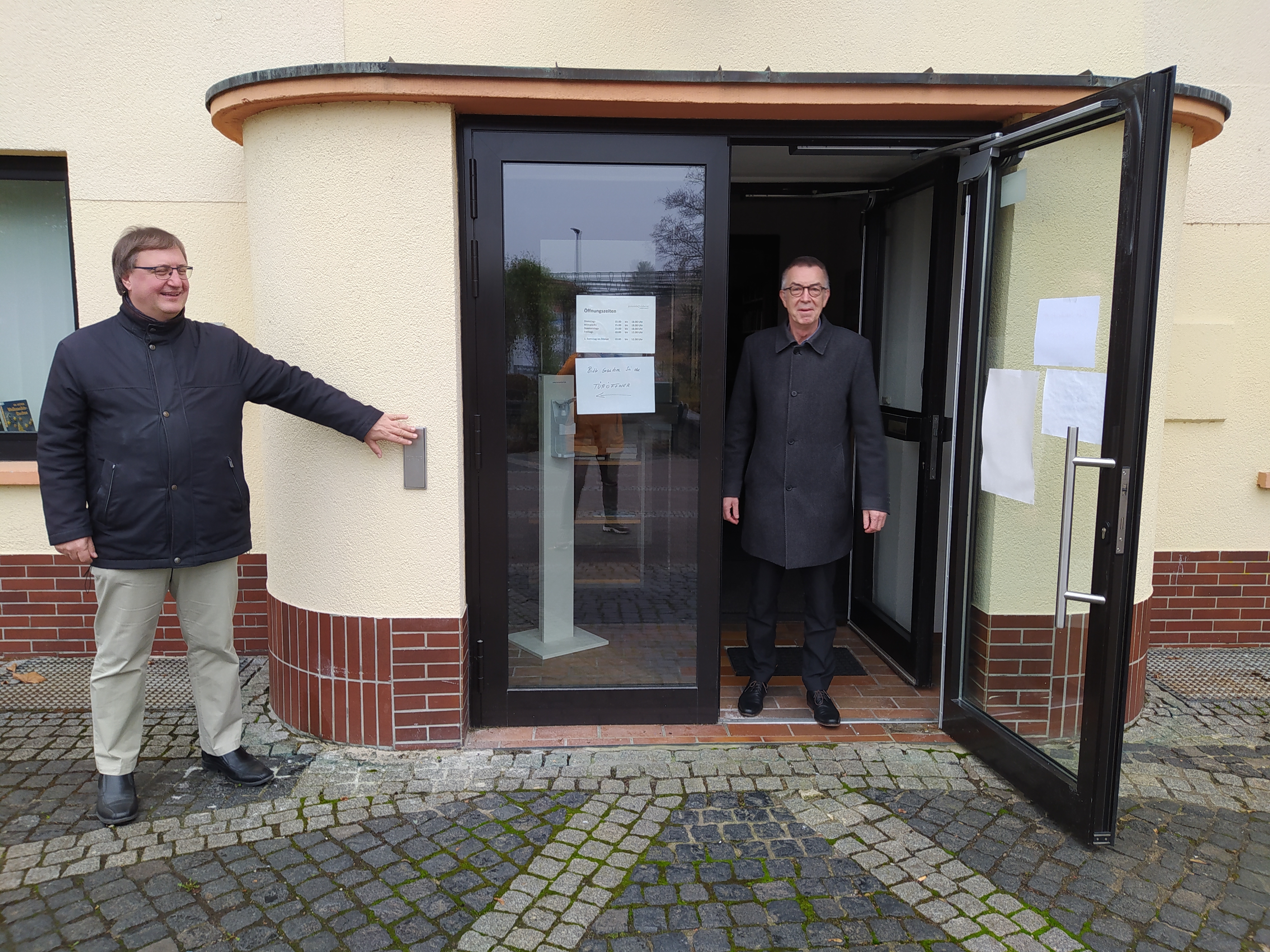 Dr. Frank Fichert öffnet per Wandtaster Franz Jirasek die Tür zur Bücherei.