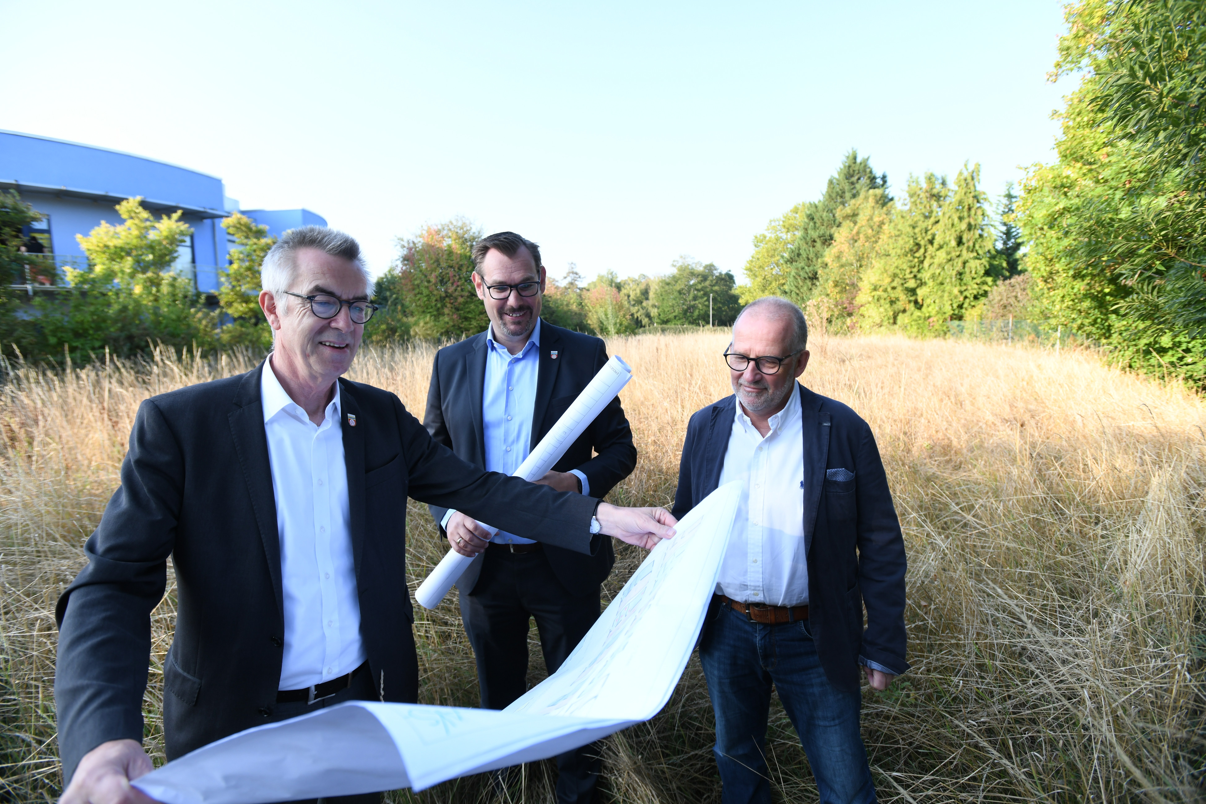Franz Jirasek, Christian Seitz und Harald Treber schauen sich auf dem Grundstück an der Raiffeisenstraße Pläne an.