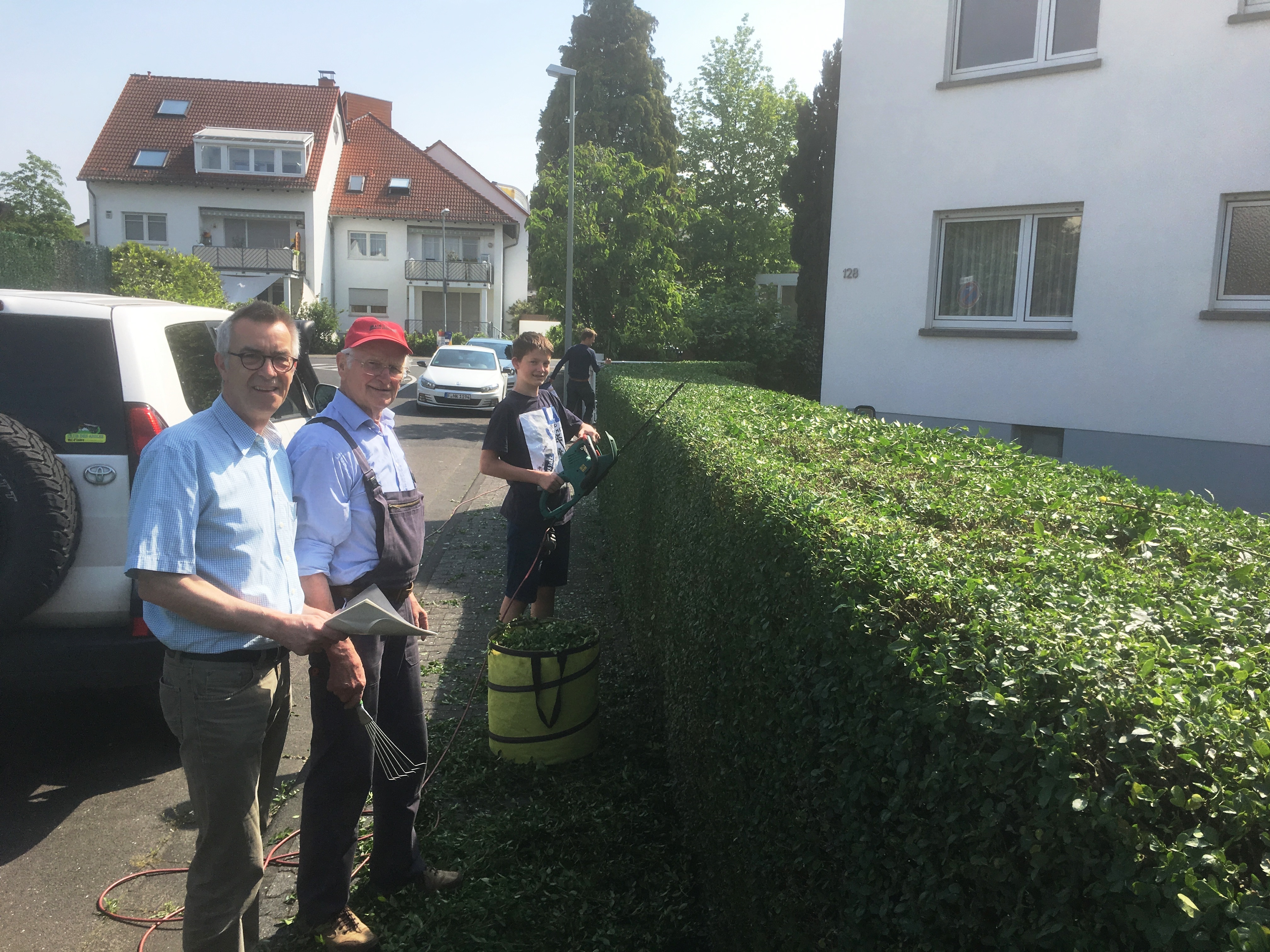 Der Erste Beigeodnete im Gespräch mit einem Bürgere, der gerade mit seinem Sohn seine Hecke schneidet.