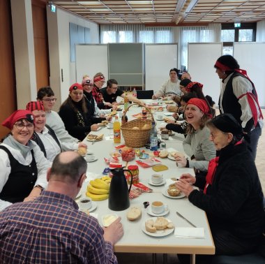 Eine lange Tafel mit Frühstückenden.