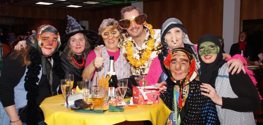 Frauen mit Hexenmasken stehen mit einem verkleideten Bürgermeister gutgelaunt an einem Stehtisch im Rathaus.
