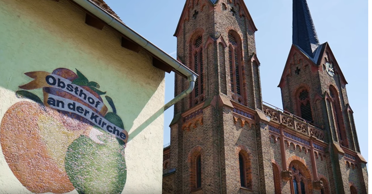 Ein Ausschnitt aus dem Film: Obsthof mit Kirche.
