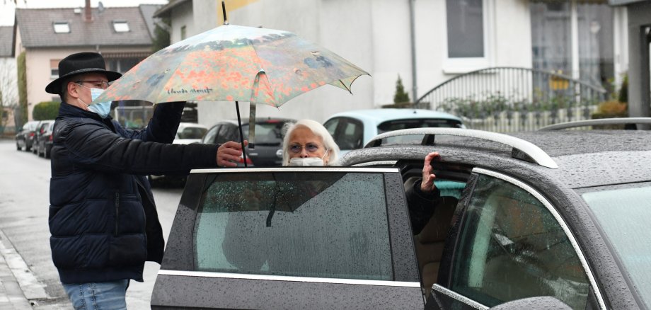 Markus Finger ist Seniorin beim Einsteigen ins Auto behilflich.