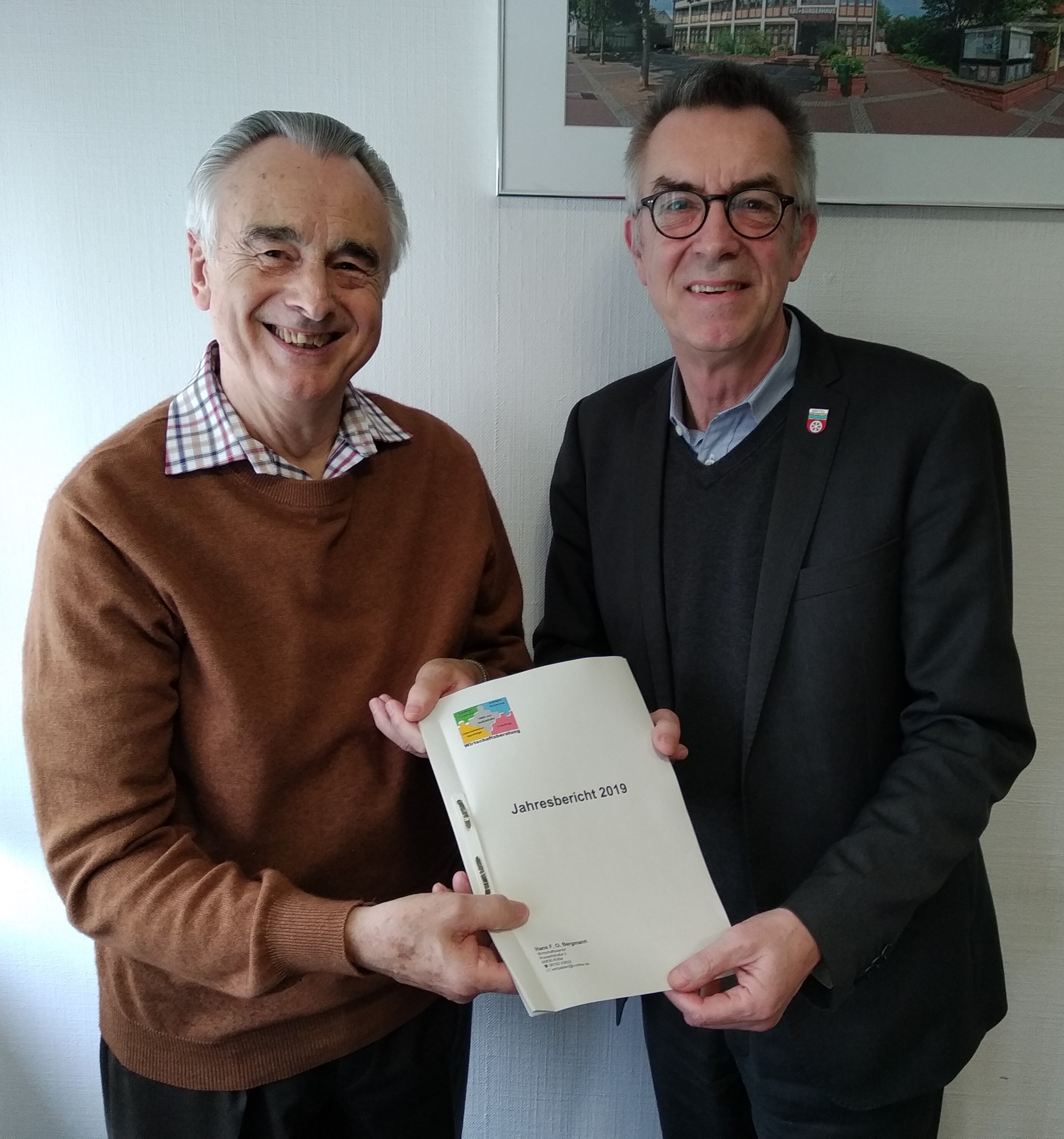 Bergmann und Jirasek stehen im Büro mit dem Jahresbericht des Wirtschaftsberaters in der Hand.