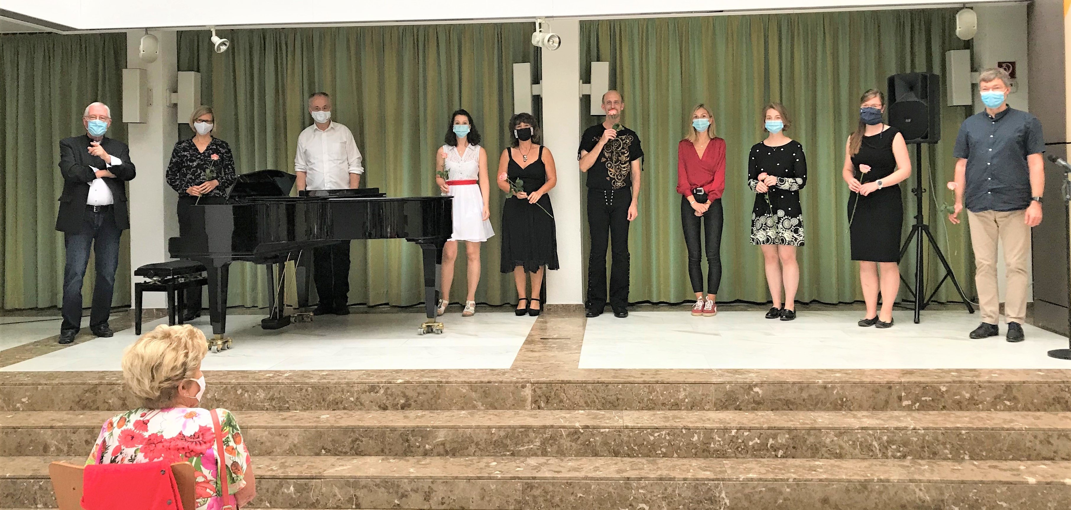 Die Künstler auf der Bühne und die Gäste tragen Maske.