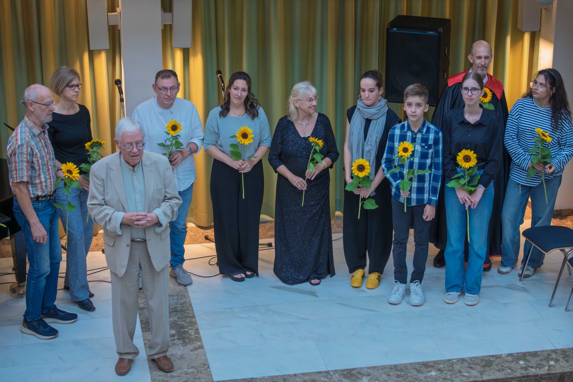 Die Teilnehmer mit Sonnenblumen auf der Bühne.