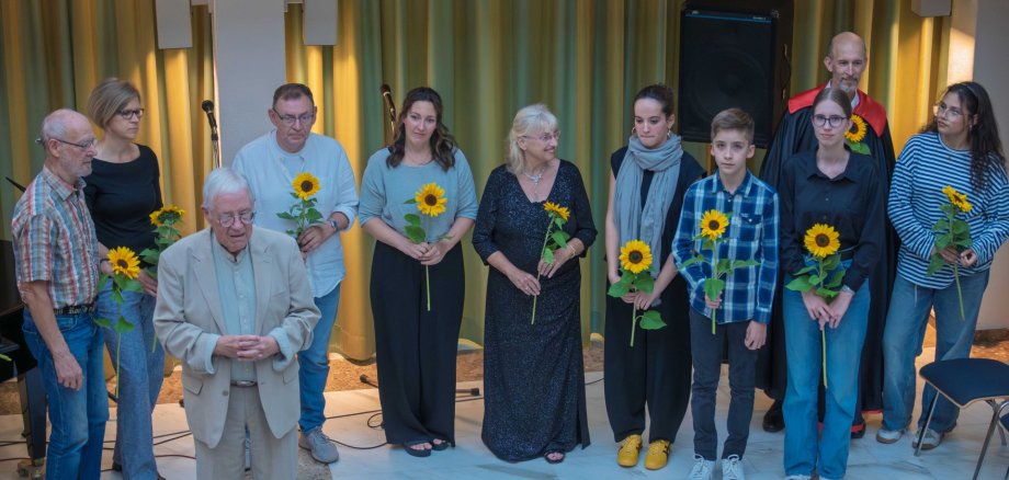 Die Teilnehmer mit Sonnenblumen auf der Bühne.