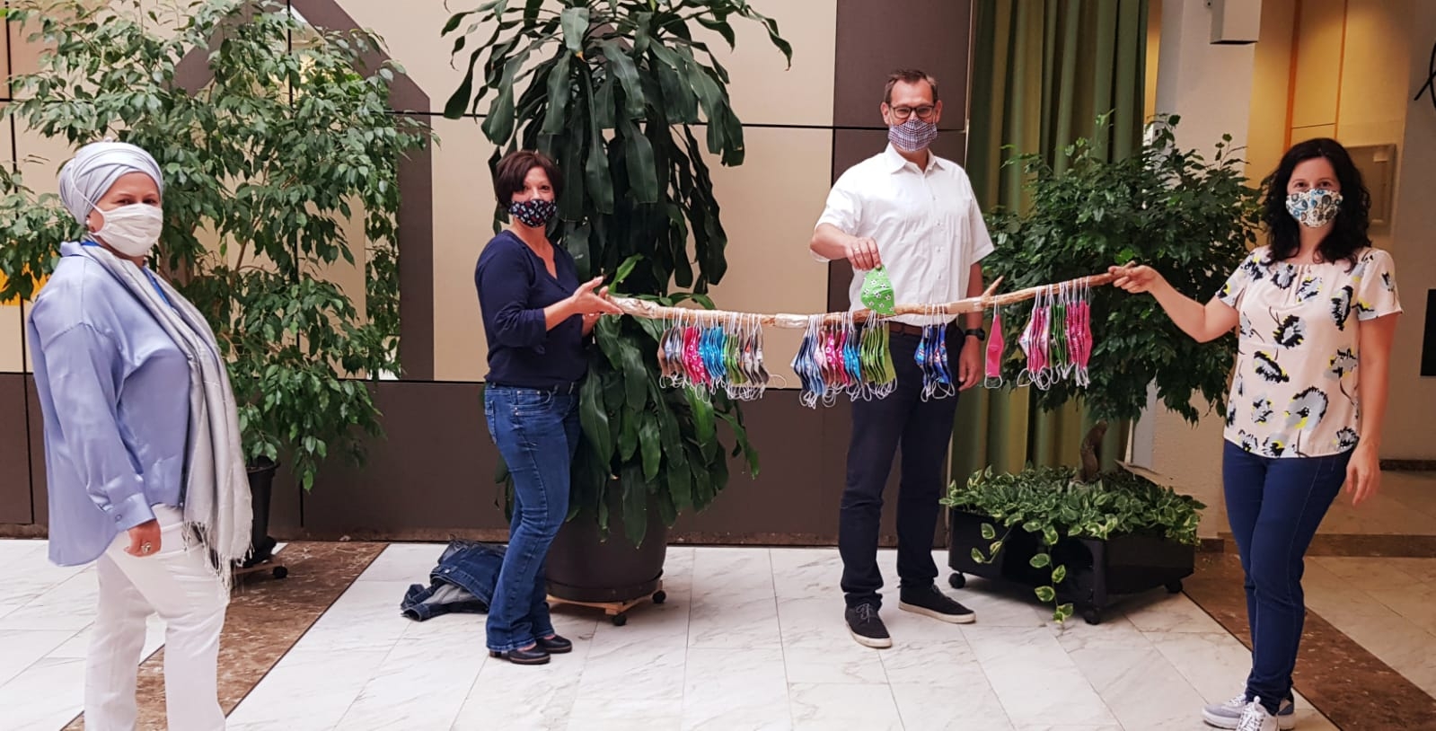 Angela Bolder mit Bürgermeister Seitz und Ljudmilla Regeniter und den bunten Masken im Foyer des Rathauses.