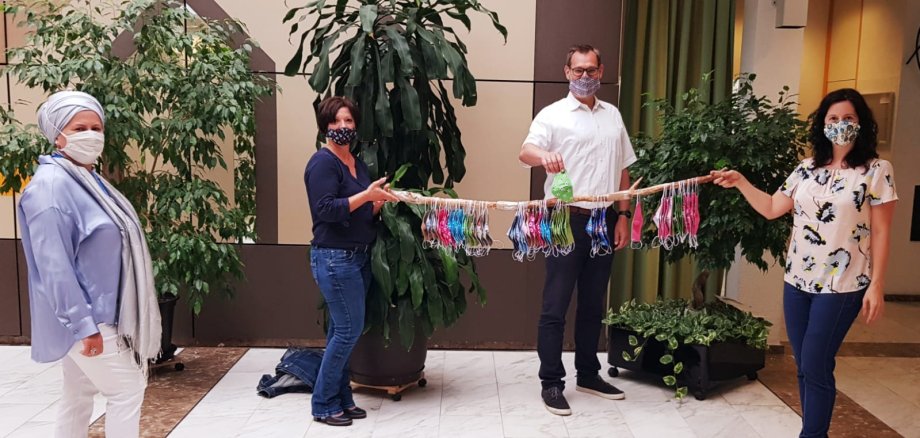 Angela Bolder mit Bürgermeister Seitz und Ljudmilla Regeniter und den bunten Masken im Foyer des Rathauses.