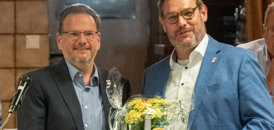 Bürgermeister Seitz übergibt Alexander Feist Blumen.
