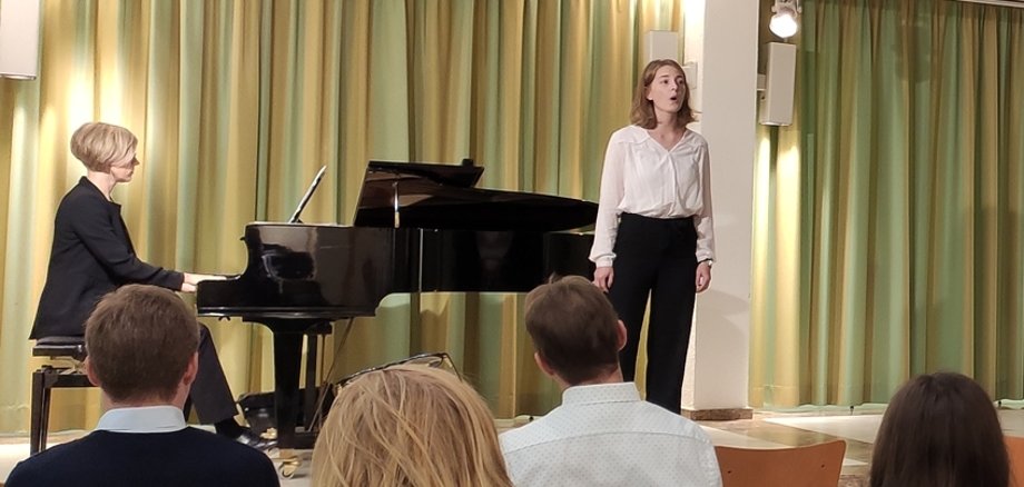 Eine Sängerin auf der Bühne neben dem Klavier.
