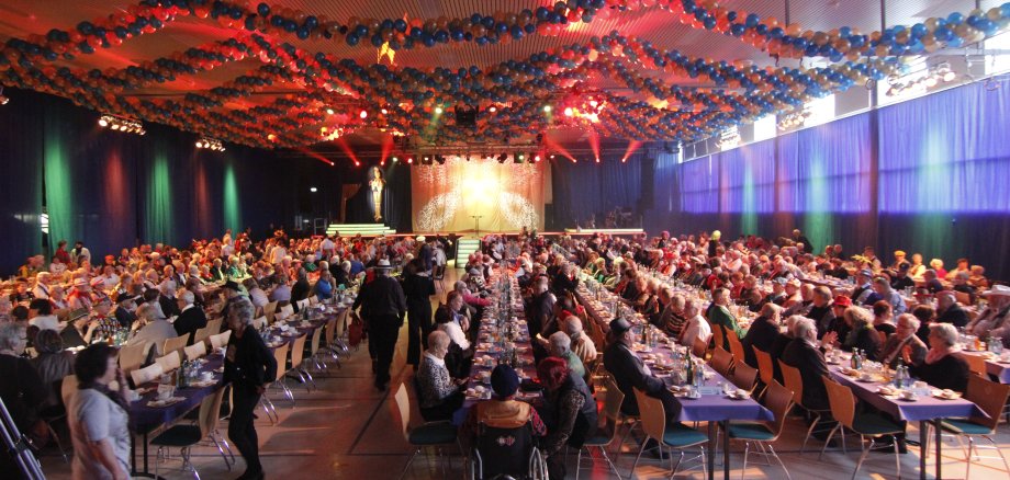 Vollbesetzte Tische in der bunt geschmückten Großen Schwarzbachhalle.