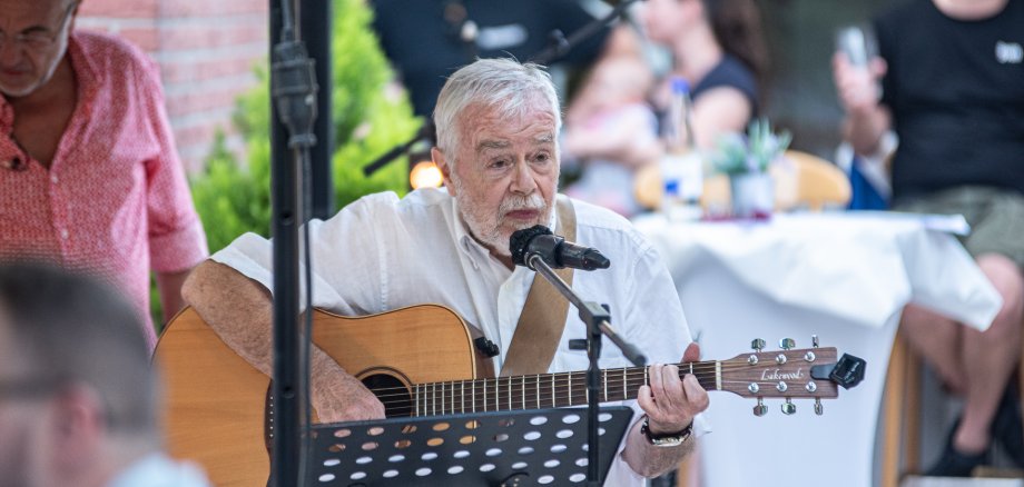 Ein Musiker mit Gitarre am Mikrofon.