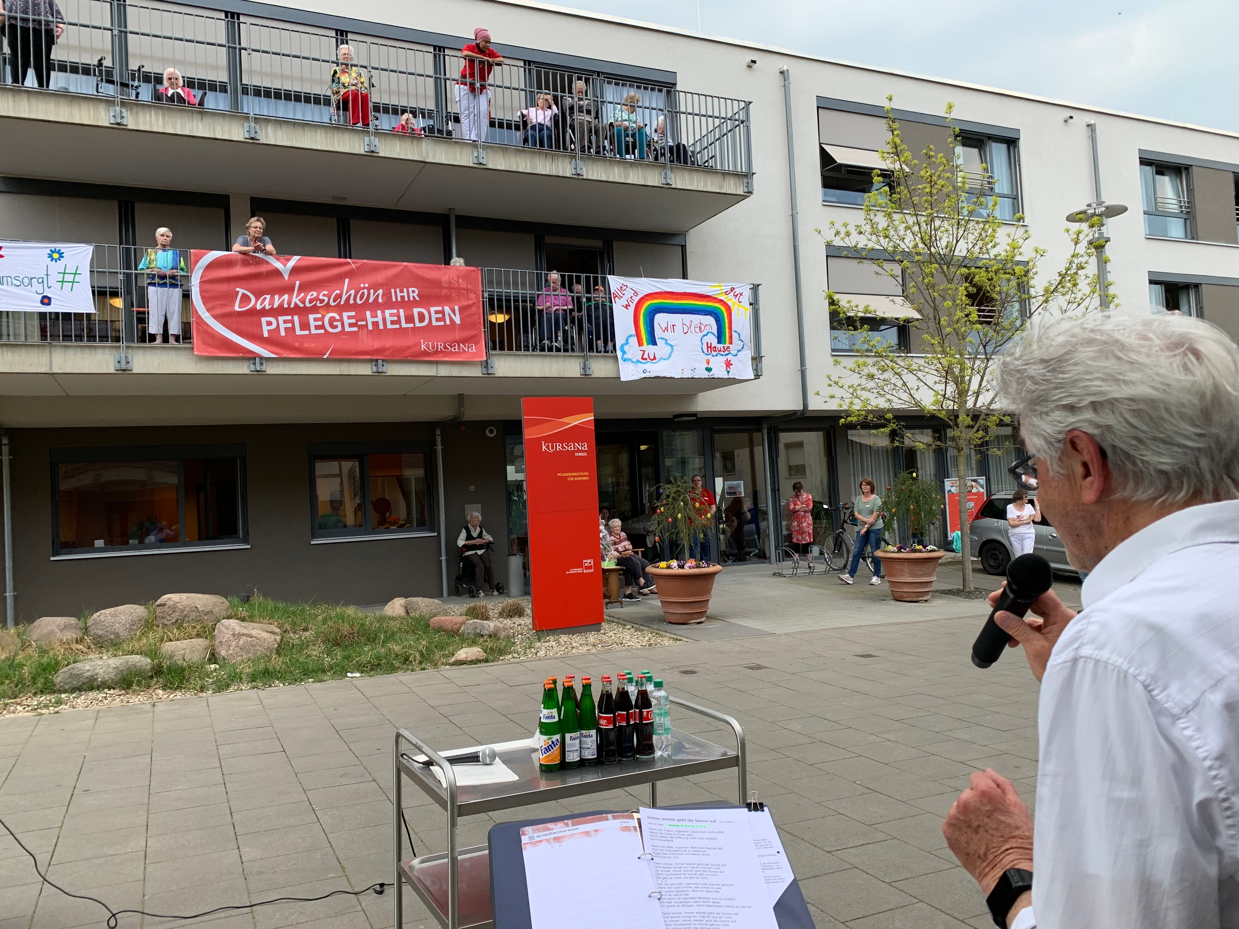 Axel Lorth mit Mikrofon vor den Balkonen des Kursana Domizils.