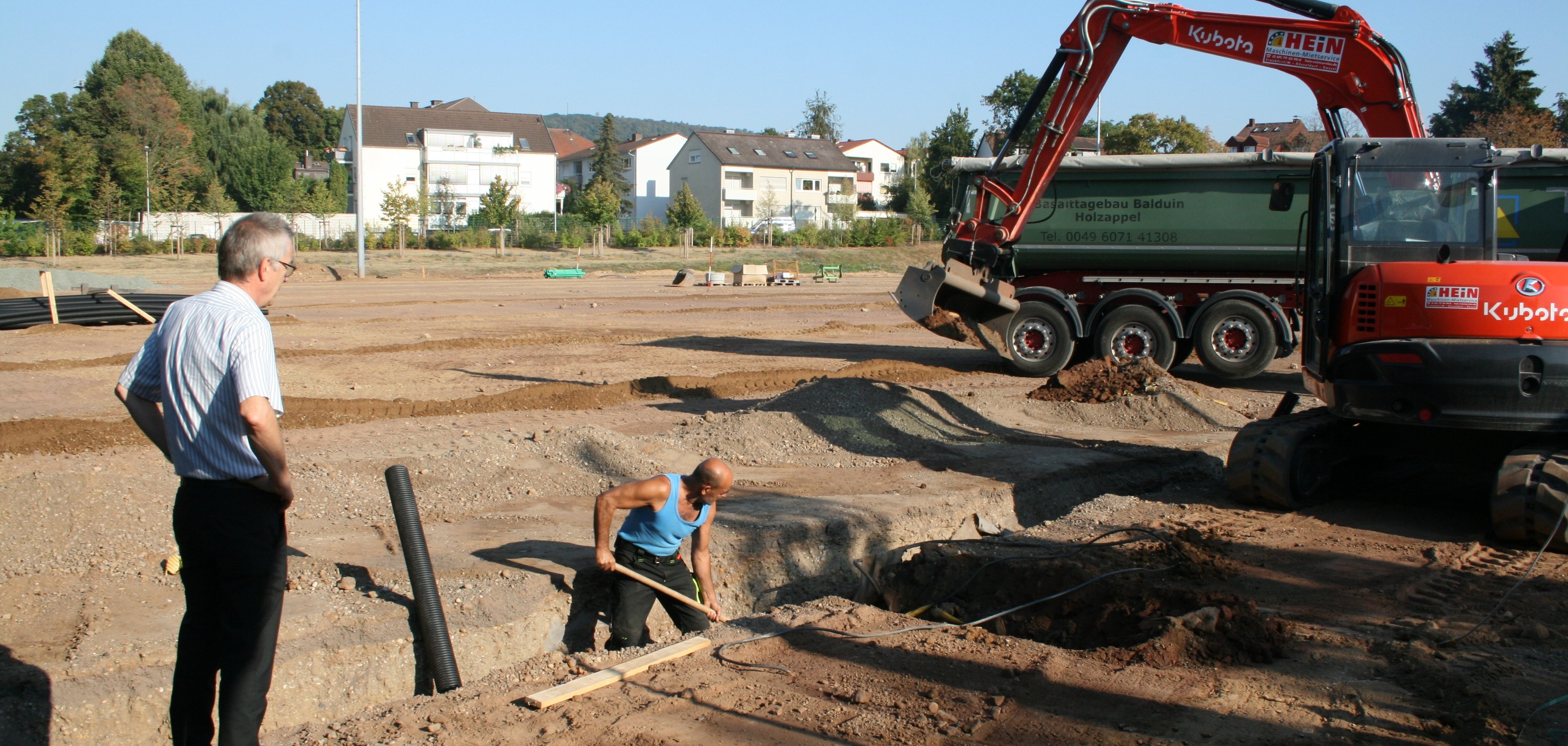 Bagger auf dem Kunstrasenplatz. Rinnen für die Drainage werden gegraben.