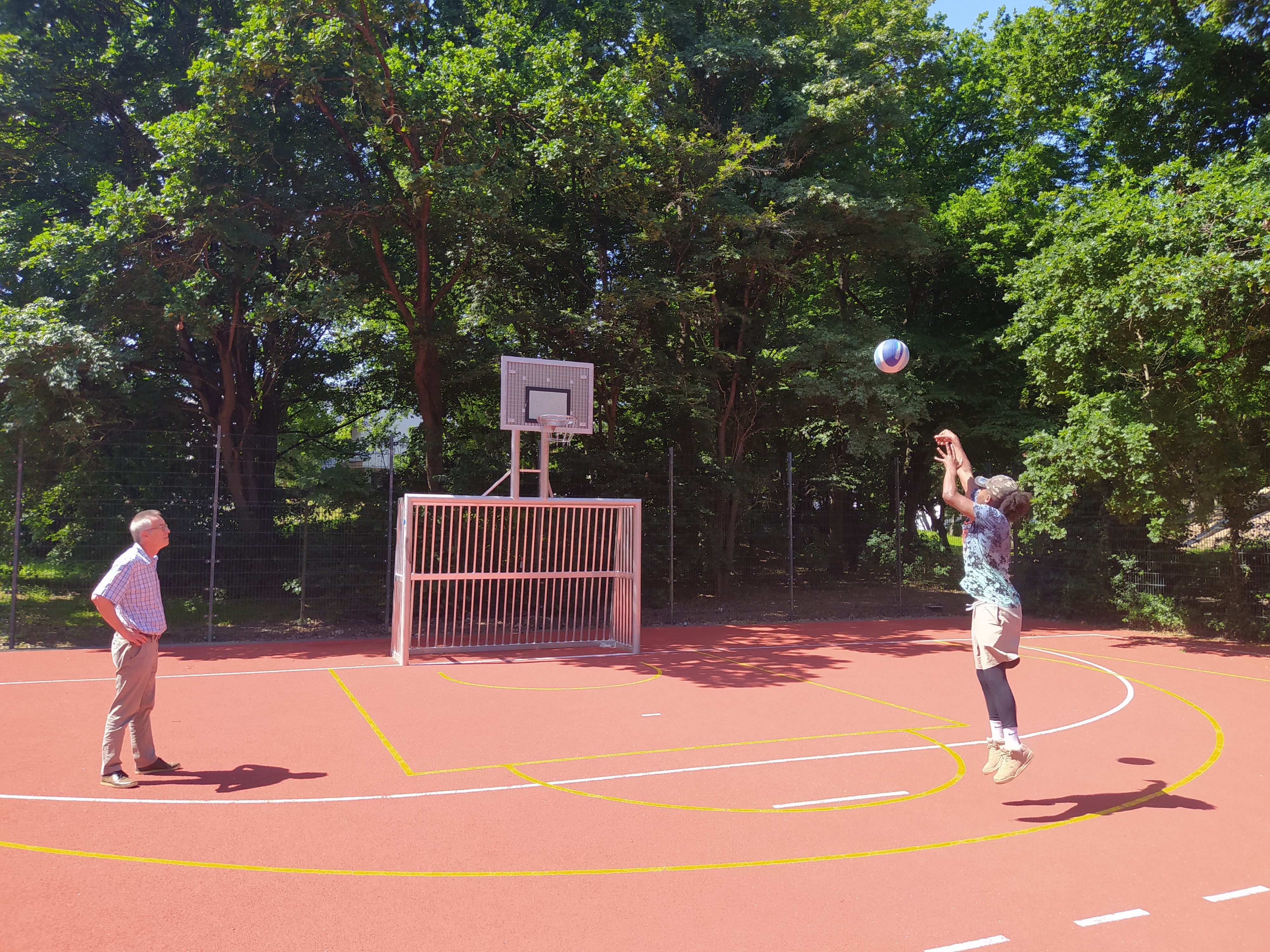 Wie ein Profi wirft ein junger Mann den Ball auf den Basketballkorb.