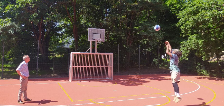 Wie ein Profi wirft ein junger Mann den Ball auf den Basketballkorb.