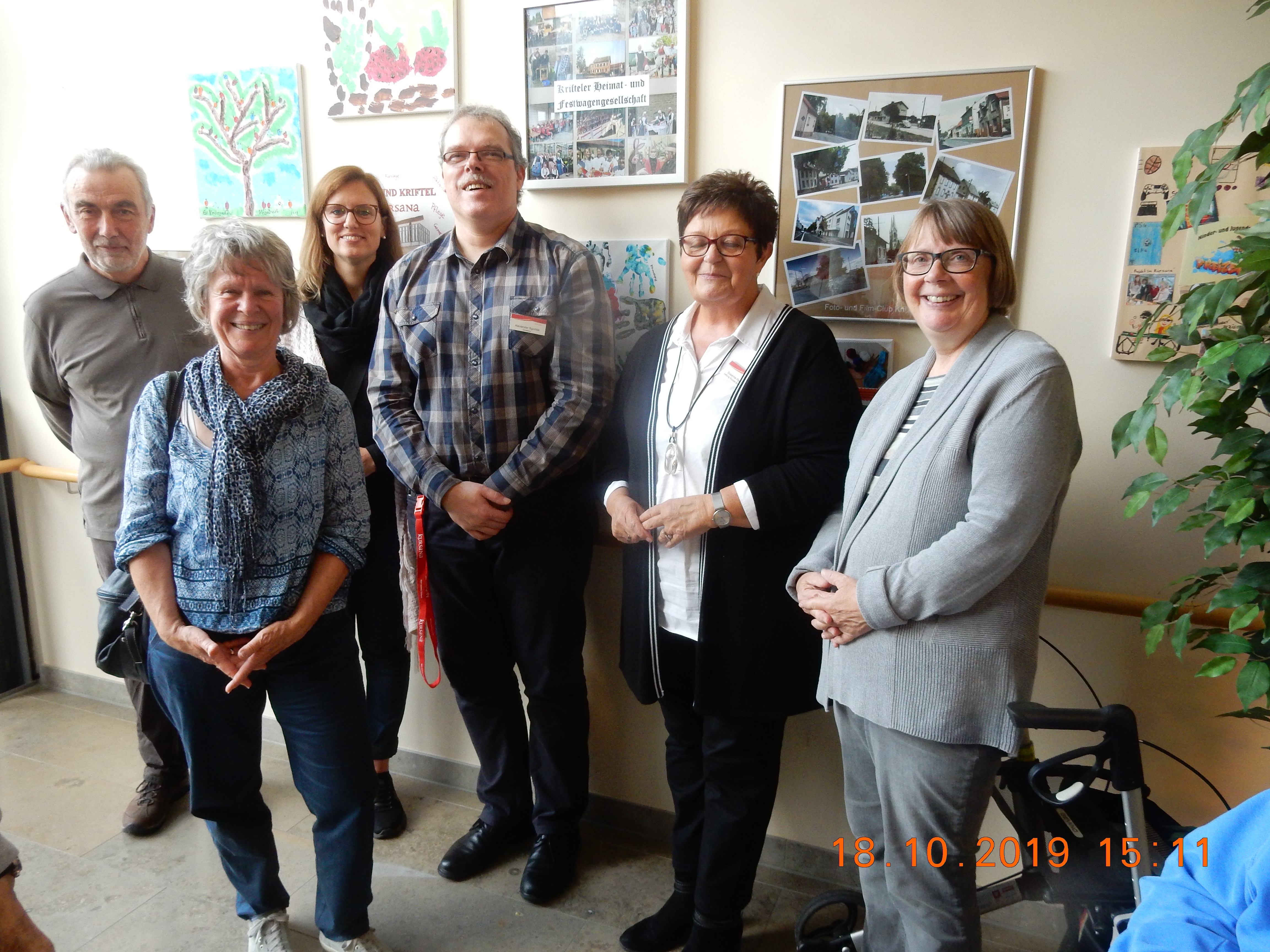 Die Leitung des Seniorenpflegeheims mit Vereinsvertretern vor der neuen Bilderwand.