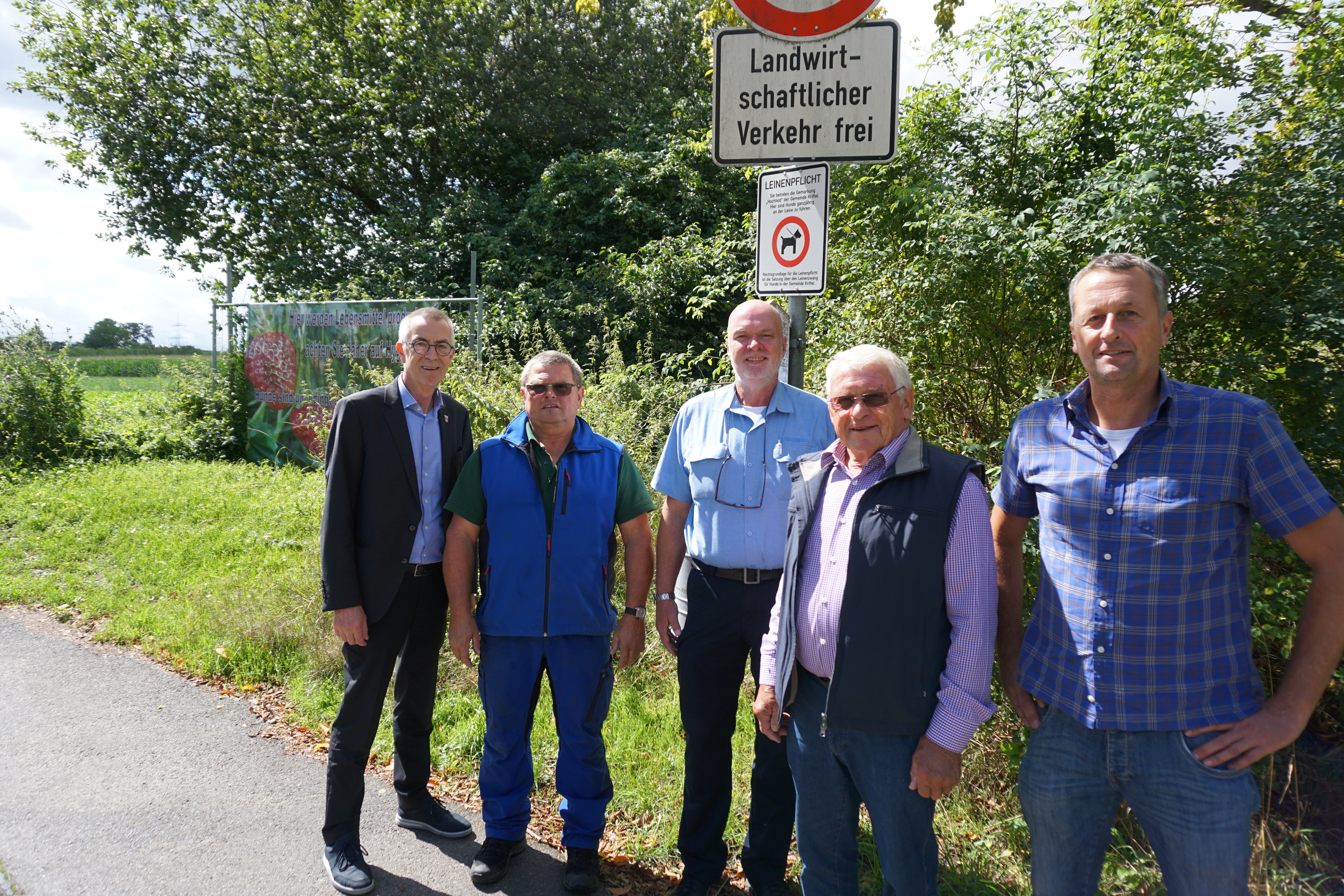 Eine Delegation unter dem neuen Hinweisschild am Eingang zum Hochfeld.
