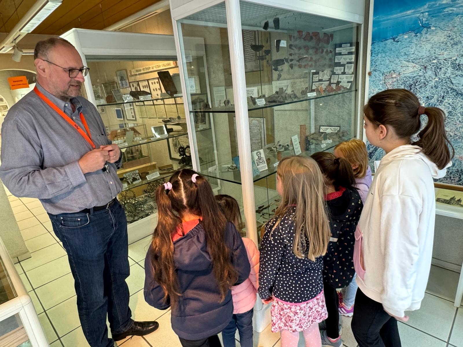 Dr. Krause mit Schülern vor einer Vitrine.