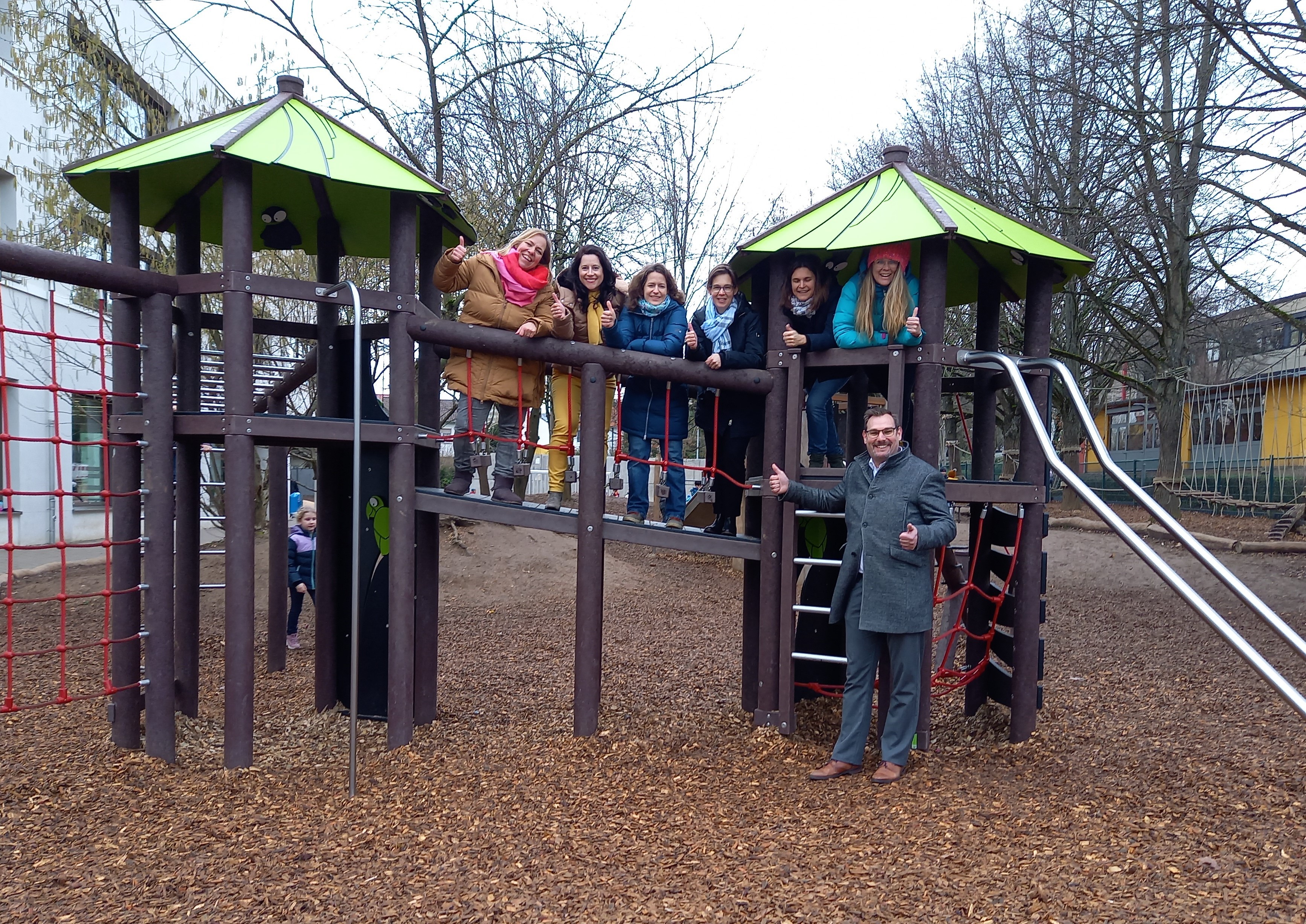 Bürgermeister und Vorstand des Fördervereins auf und vor einem Spielgerät.