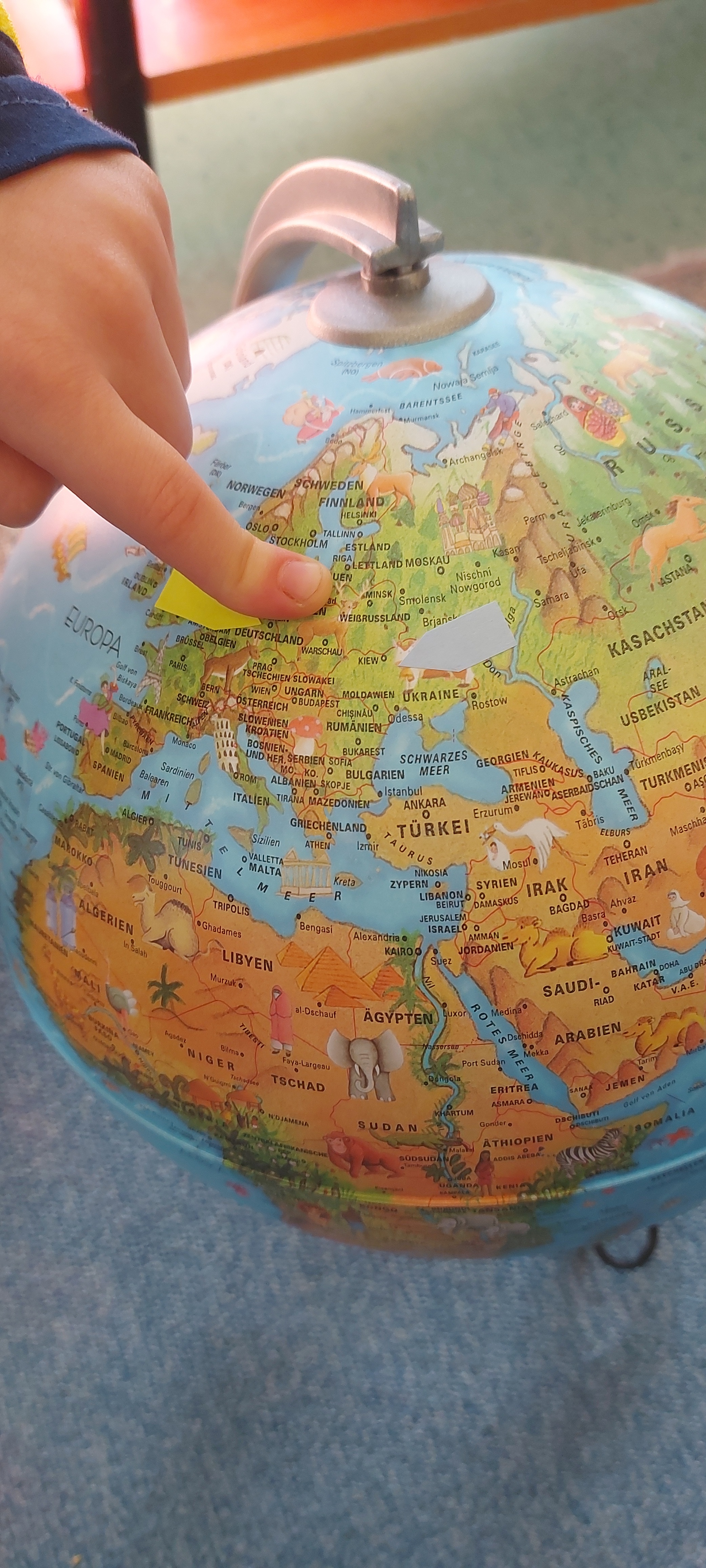 Ein KInderfinger zeigt auf einer Weltkugel auf die Ukraine.